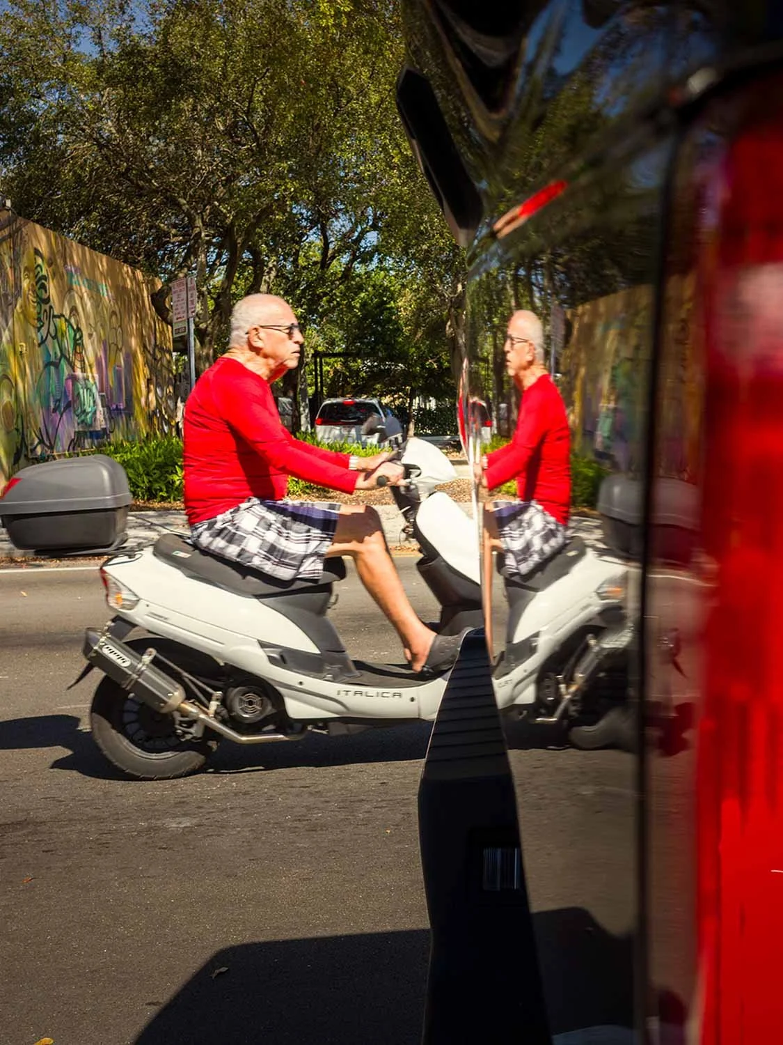 Scooter rider in a red shirt passing through a street in Little Havana, Miami