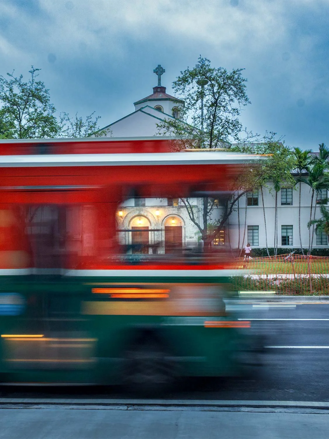 Miami trolley in motion blur passing in front of a white church in Coral Gables on an overcast evening