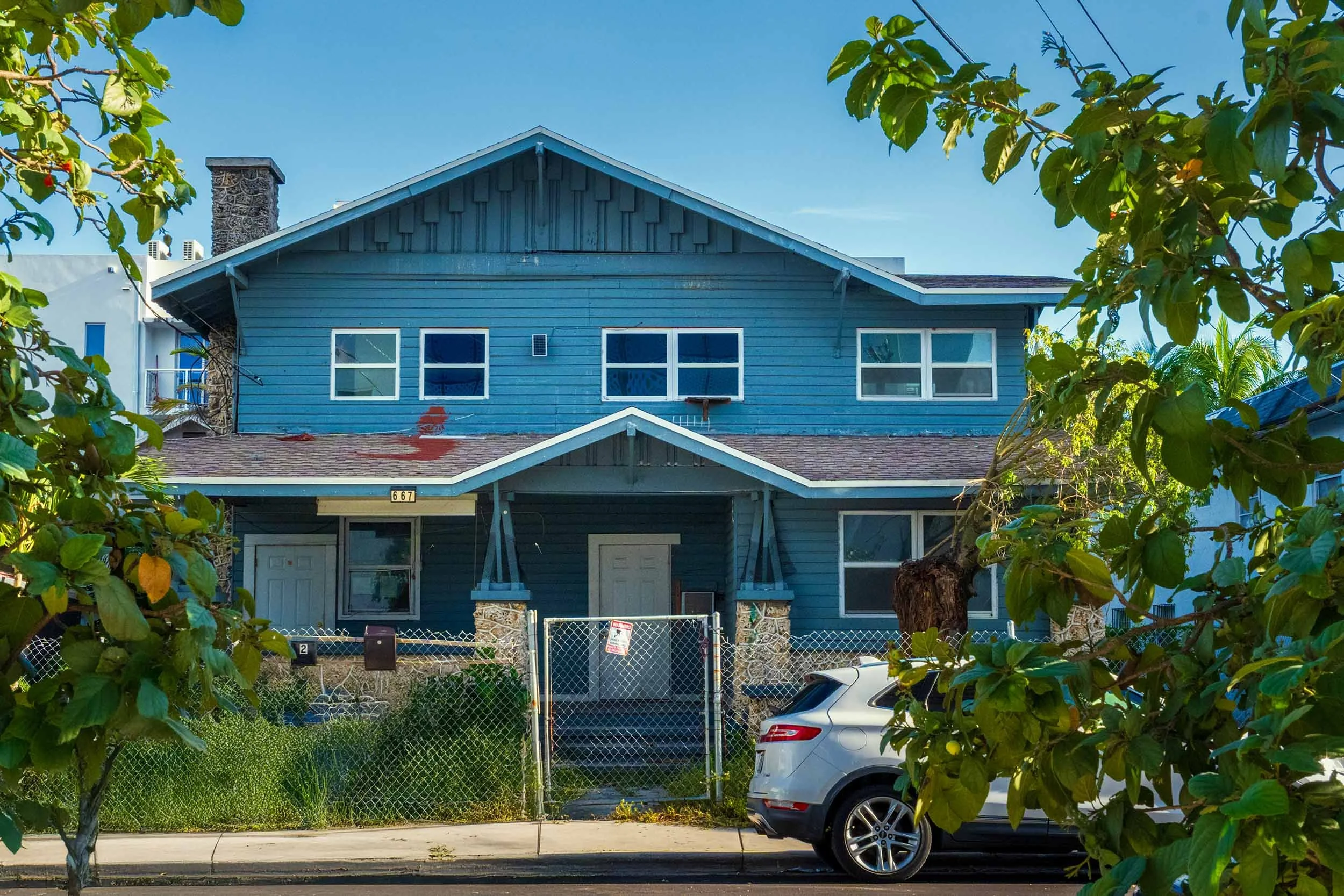 Blue two-story Craftsman house with a stone chimney in Miami