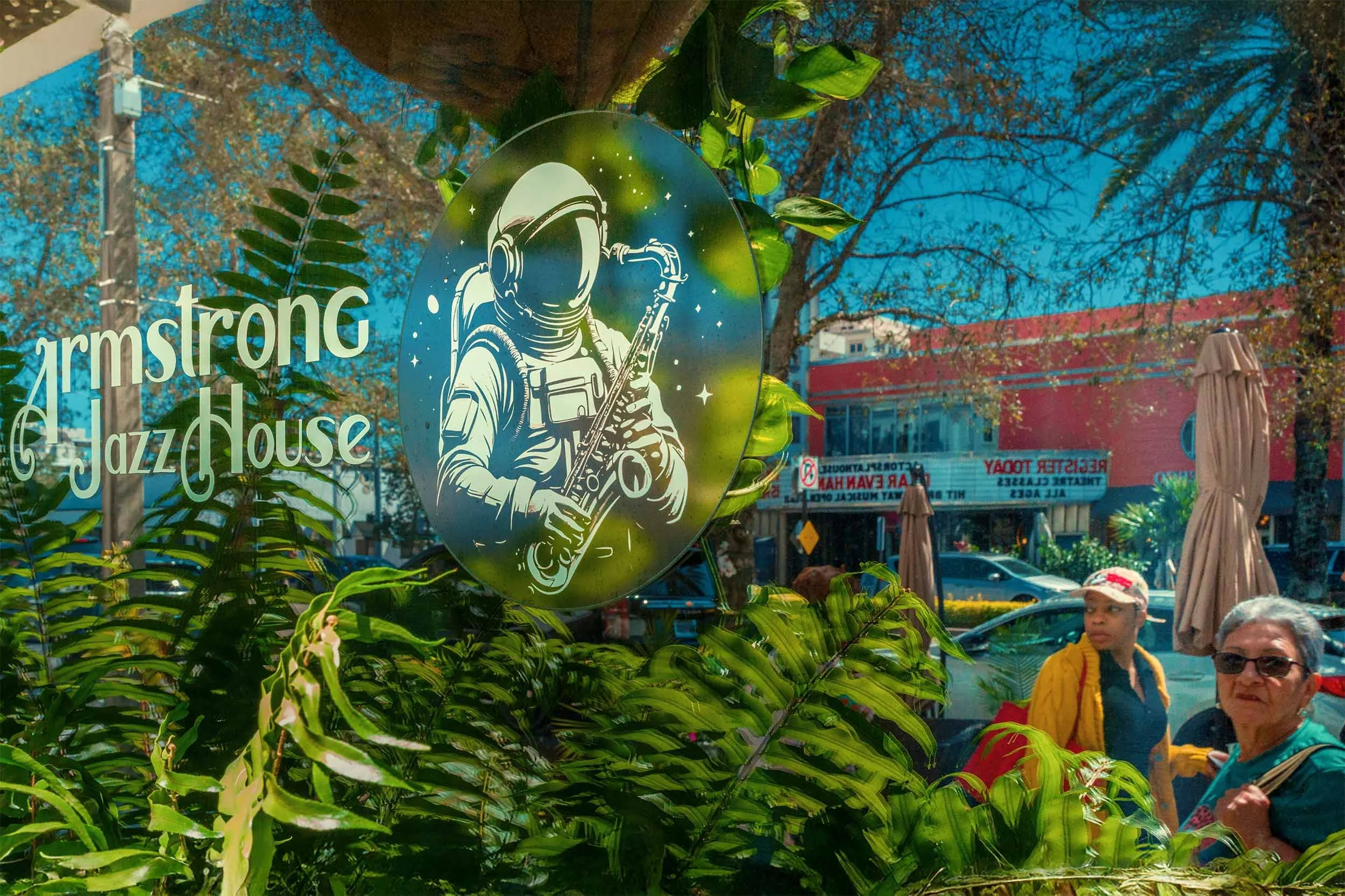 Armstrong Jazz House storefront window in Coral Gables with an astronaut saxophone illustration and street reflection