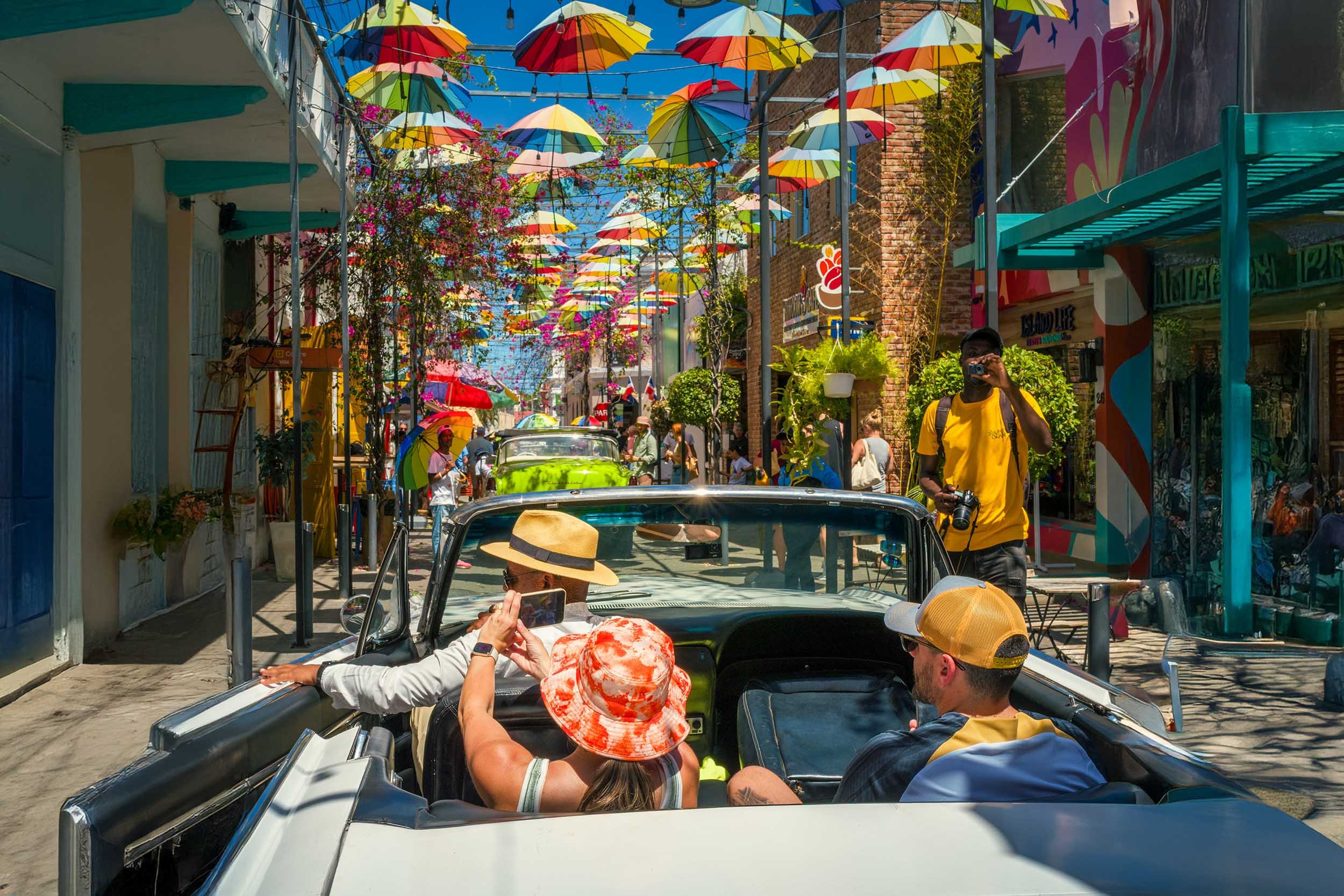 Tourists in a classic convertible under colorful hanging umbrellas in Puerto Plata, Dominican Republic