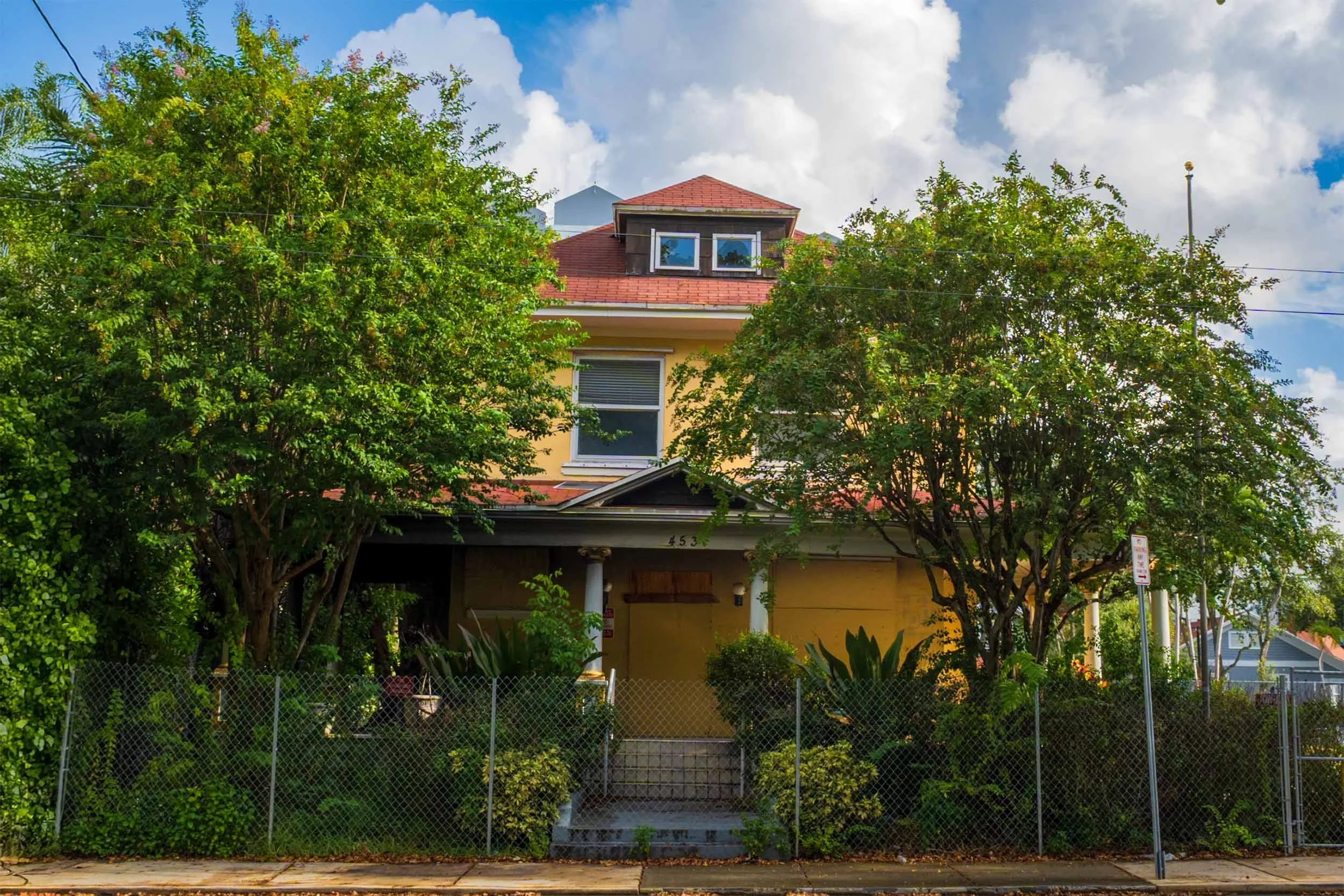 Yellow historic house shaded by trees in the district