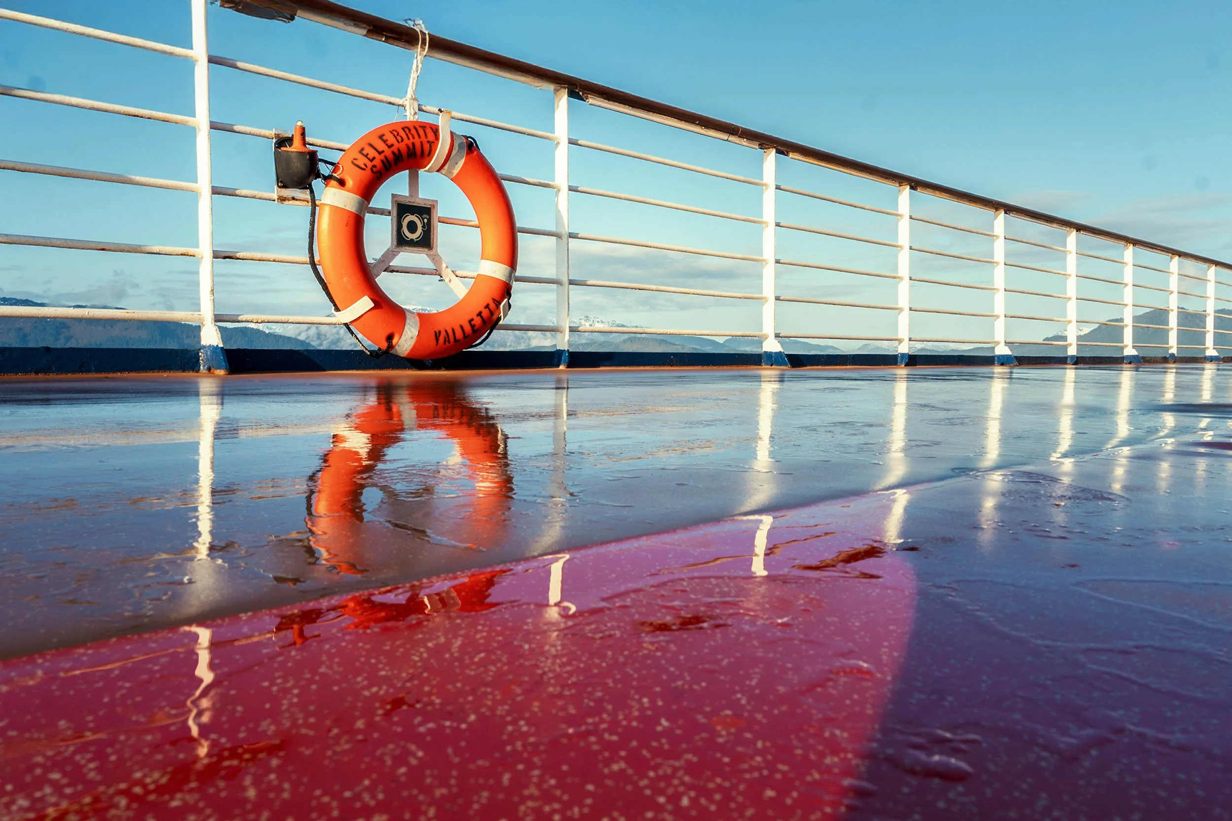 Life ring reflected on a rain-soaked cruise ship deck
