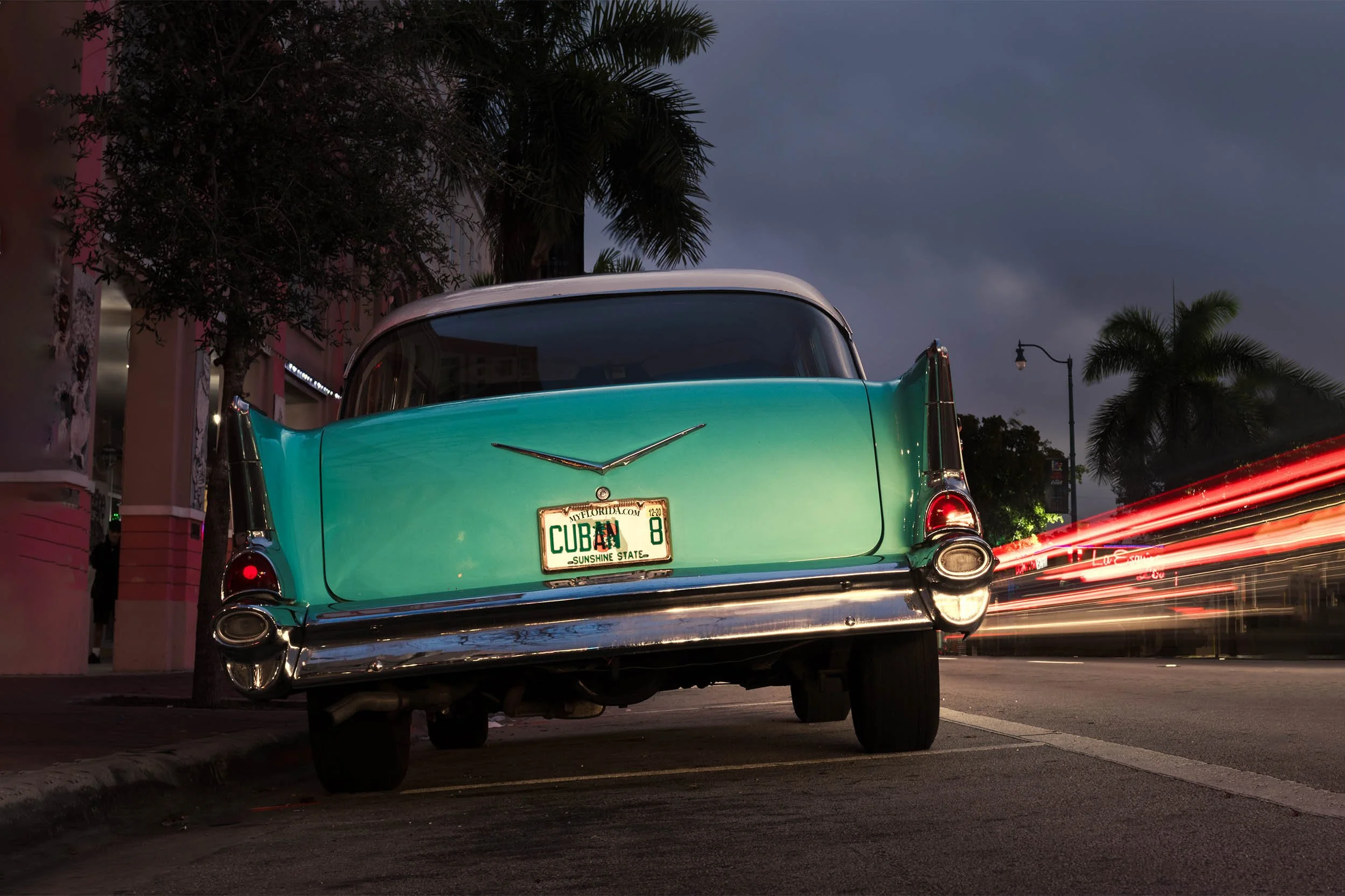 Night time light trails on Calle Ocho stream pasted a classic car.