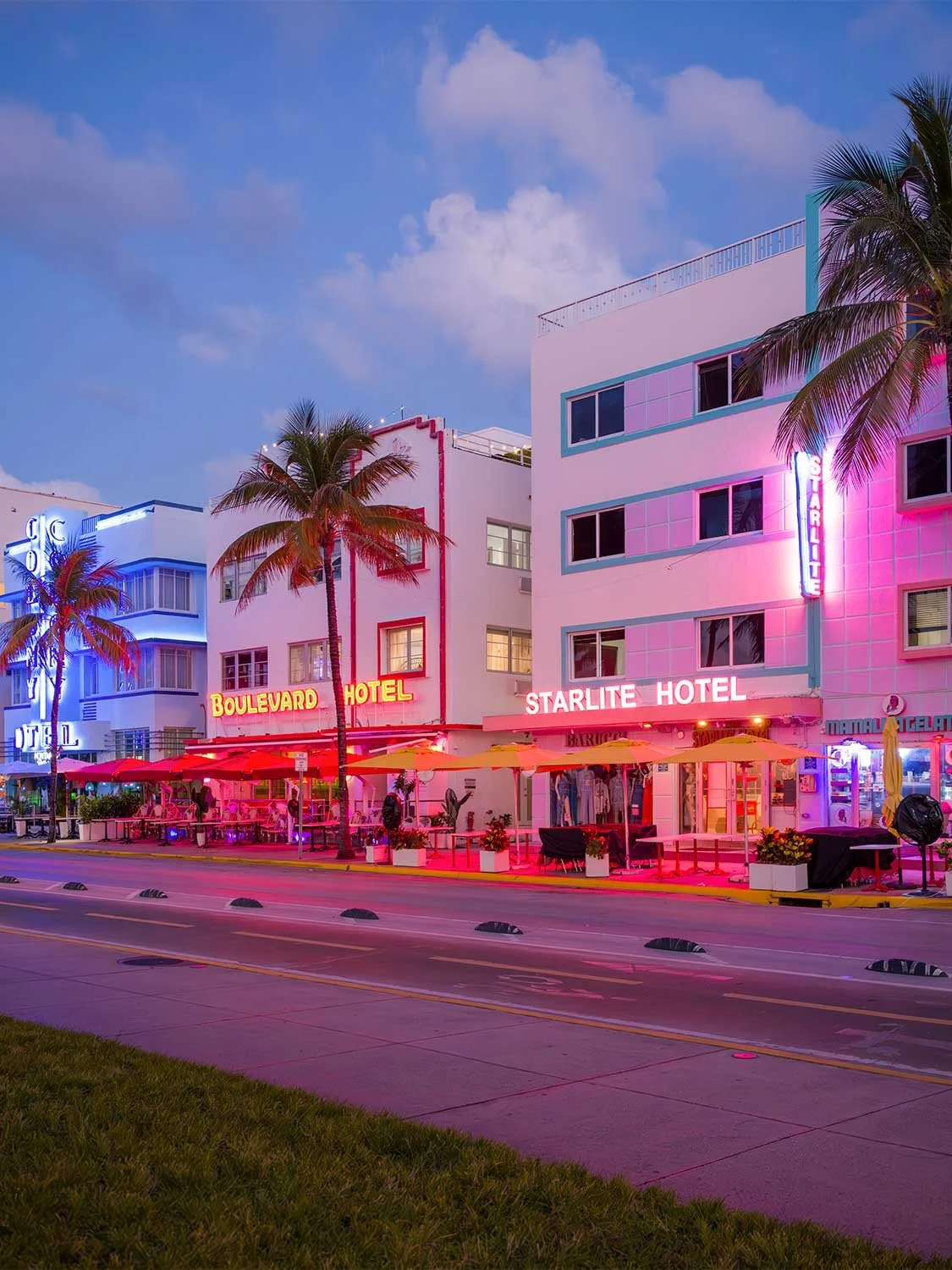Neon-lit Boulevard and Starlite Hotels on Ocean Drive, South Beach at dusk with palm trees and outdoor seating.