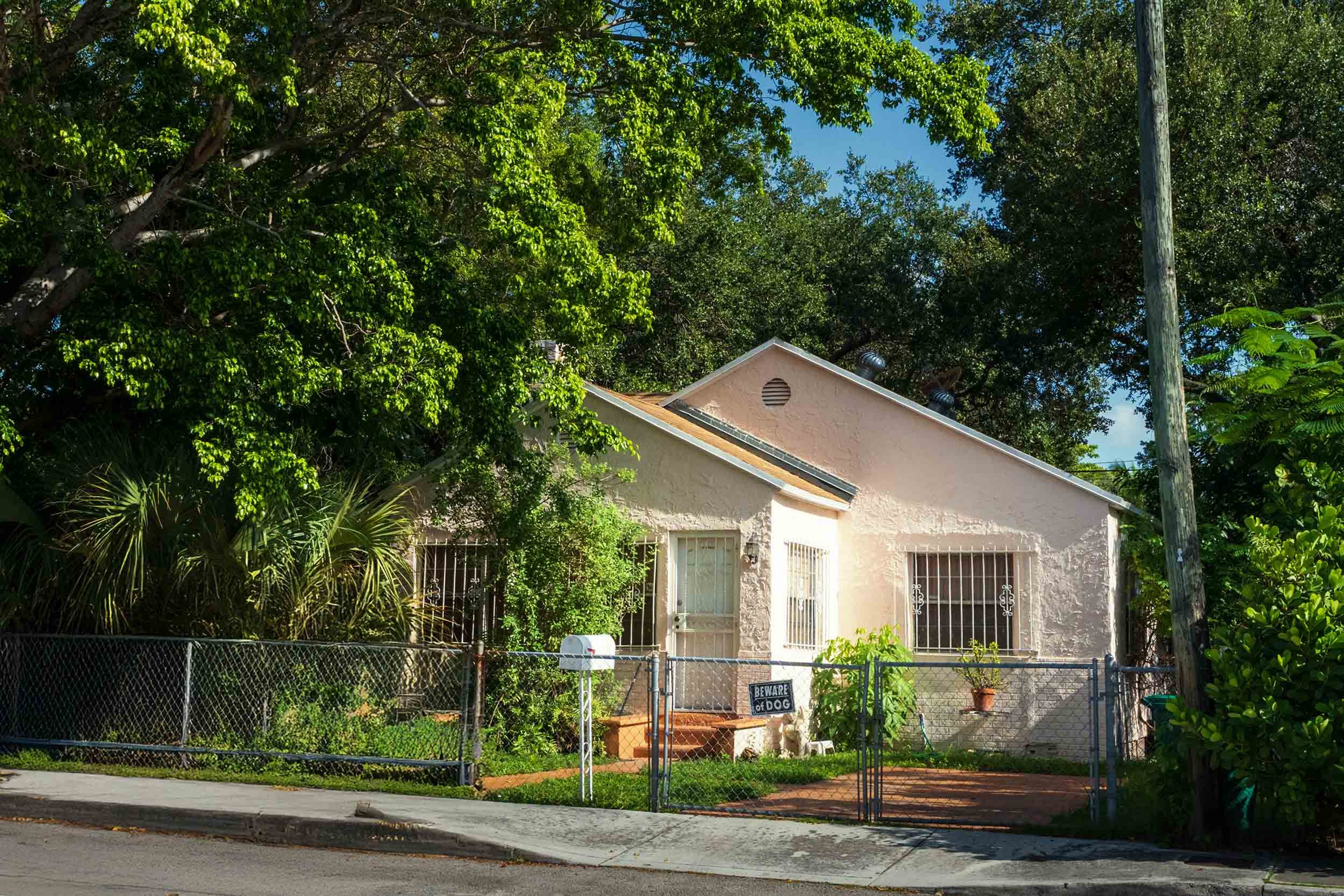 1920s pink stucco cottage behind a chain-link fence, Buena Vista Miami