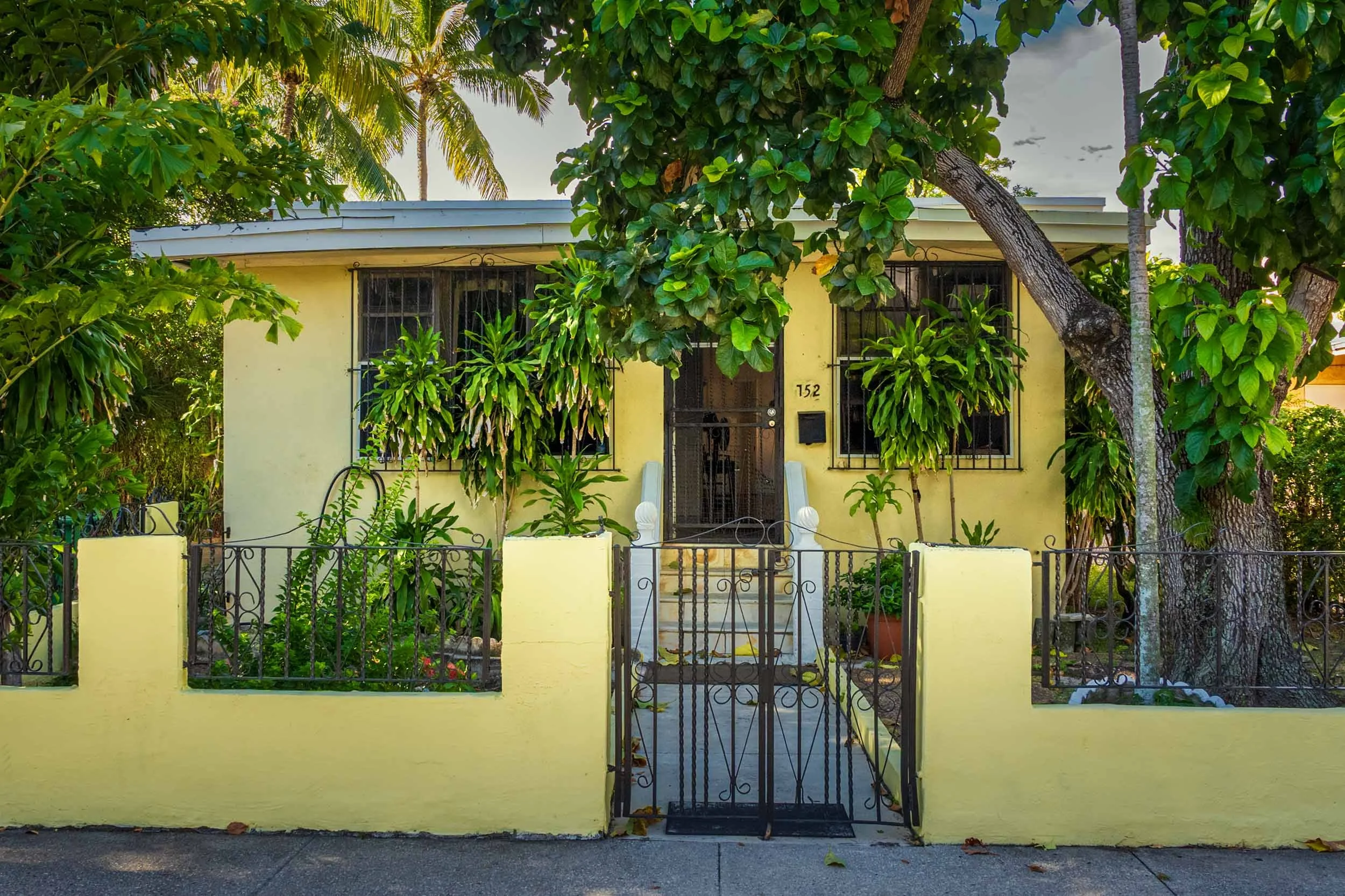 Yellow wood-frame cottage behind a wrought-iron gate in Miami's River District