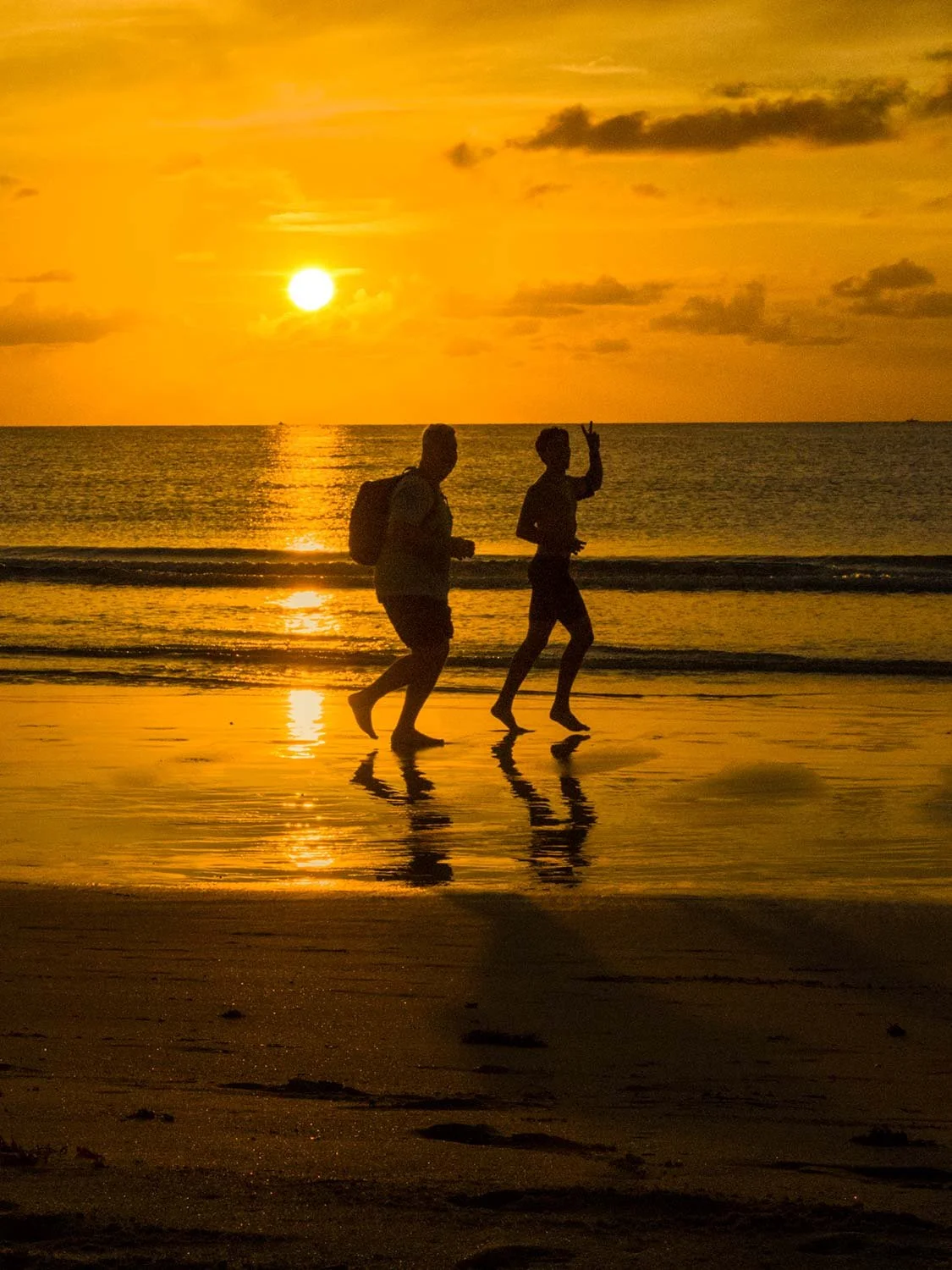Two people running along the shoreline at sunset on South Beach Miami