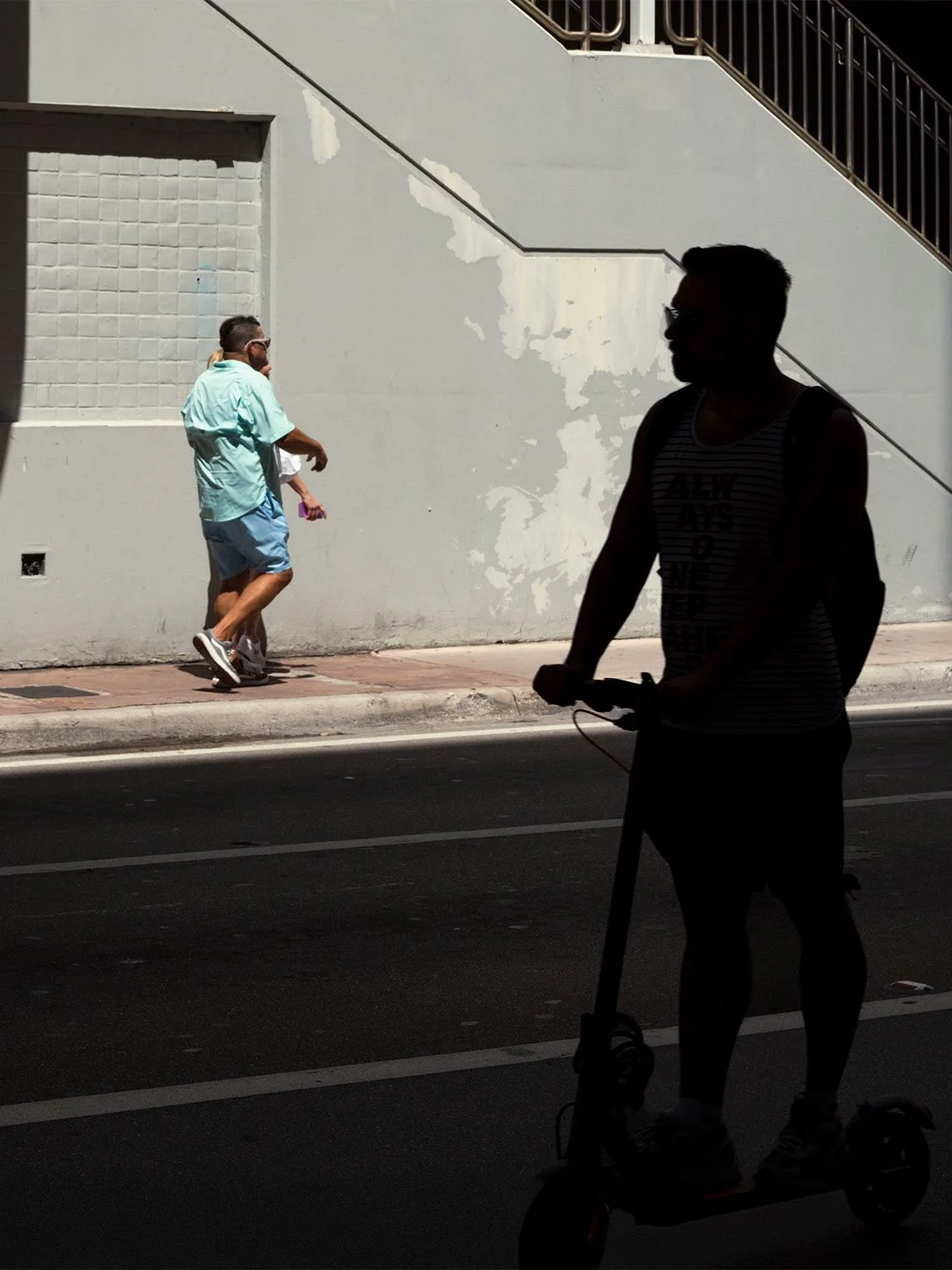 Electric scooter rider on city street with pedestrians, urban micro-mobility transportation in sunny downtown area.