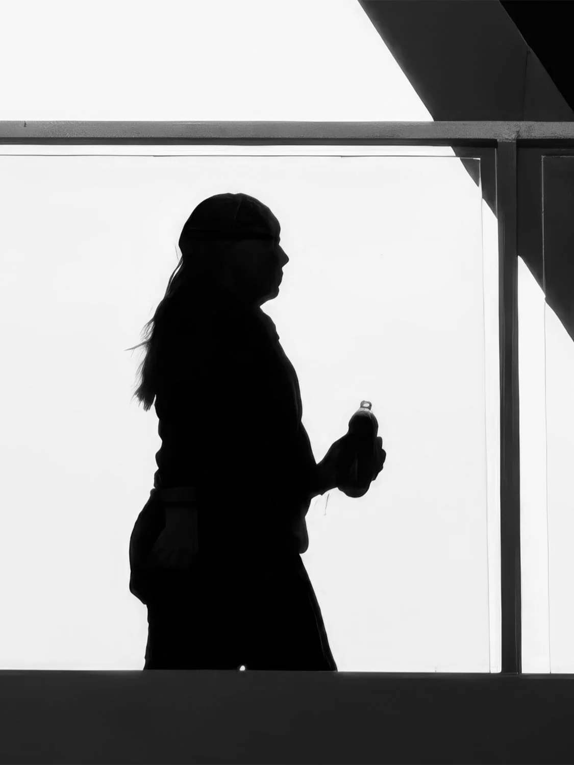 Silhouette of a woman holding a water bottle against a bright white background in Brickell