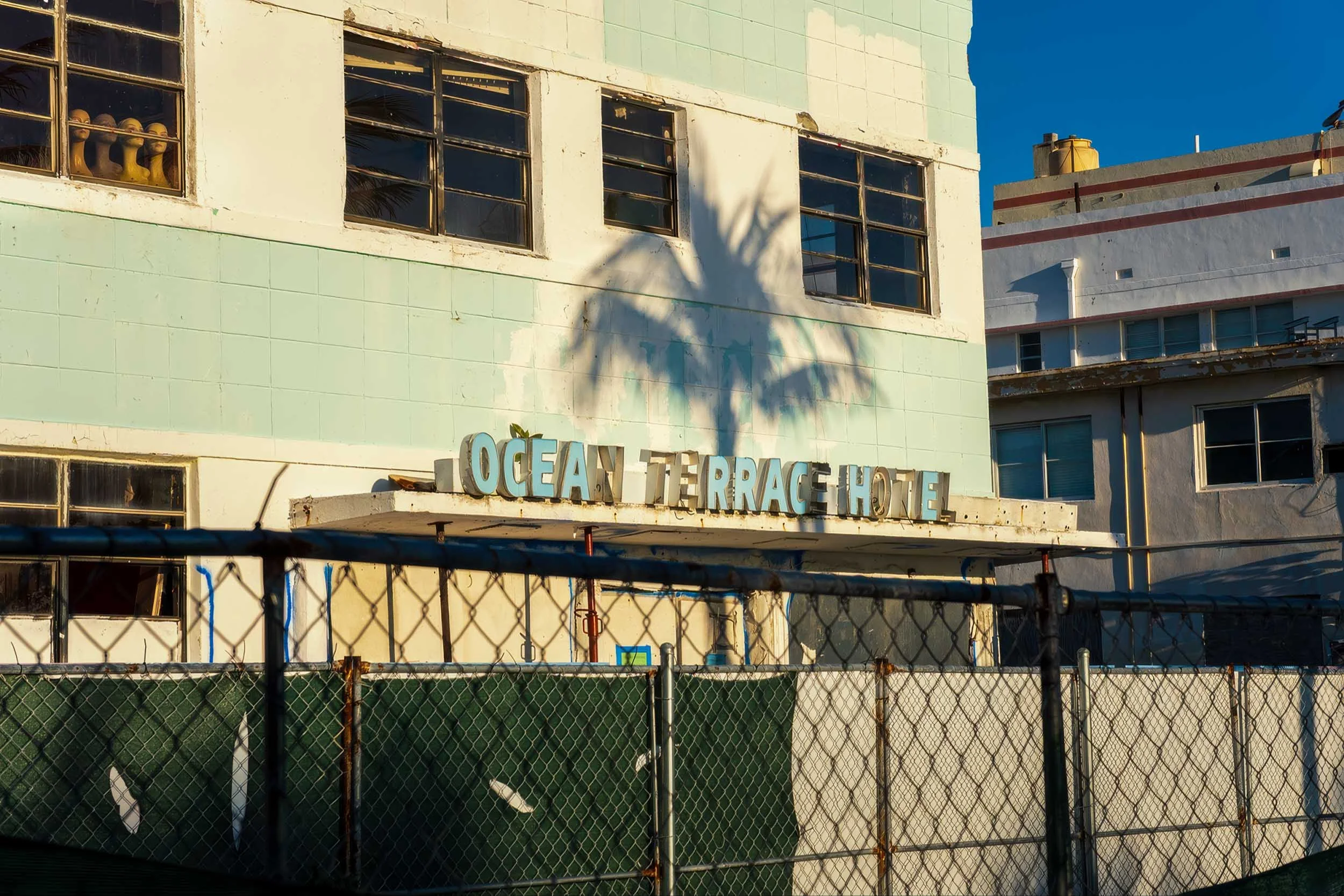 OCEAN TERRACE HOTEL sign above entrance canopy with graffiti and palm shadow, North Beach Miami