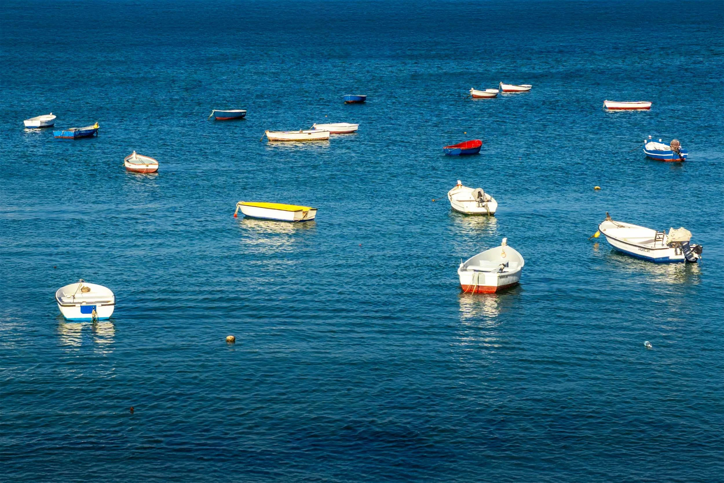 Cadiz Spain fishing boats sea | traditional wooden rowboats anchored Mediterranean blue harbor