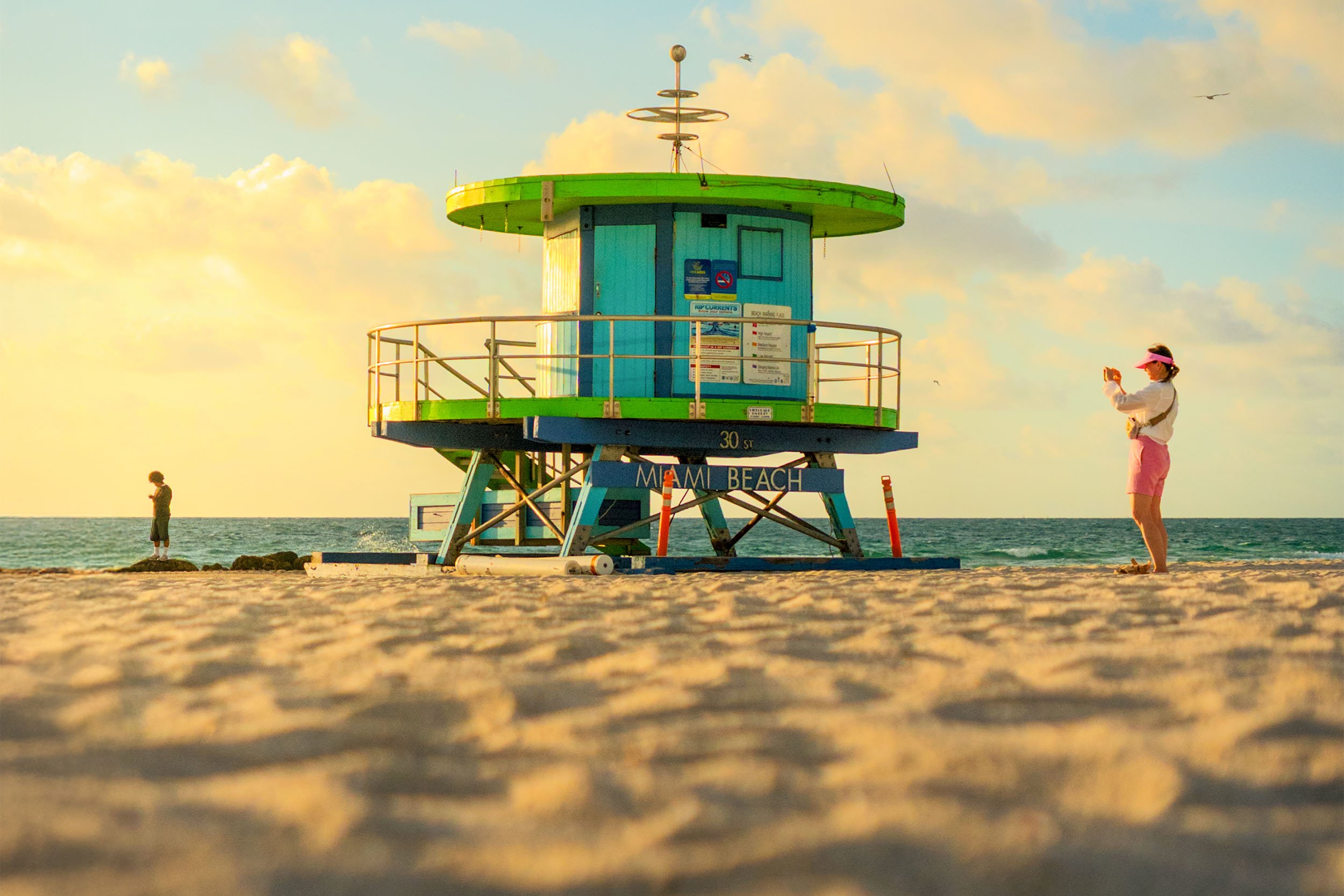 A tourist taking a picture of one of the icon lifeguard towers on South Beach in Miami Beach
