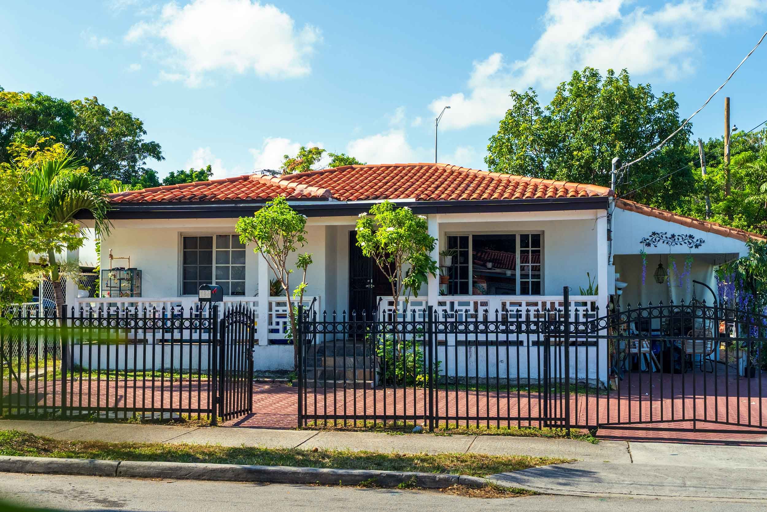 Spanish tile-roof home behind a black wrought iron fence, Buena Vista Miami