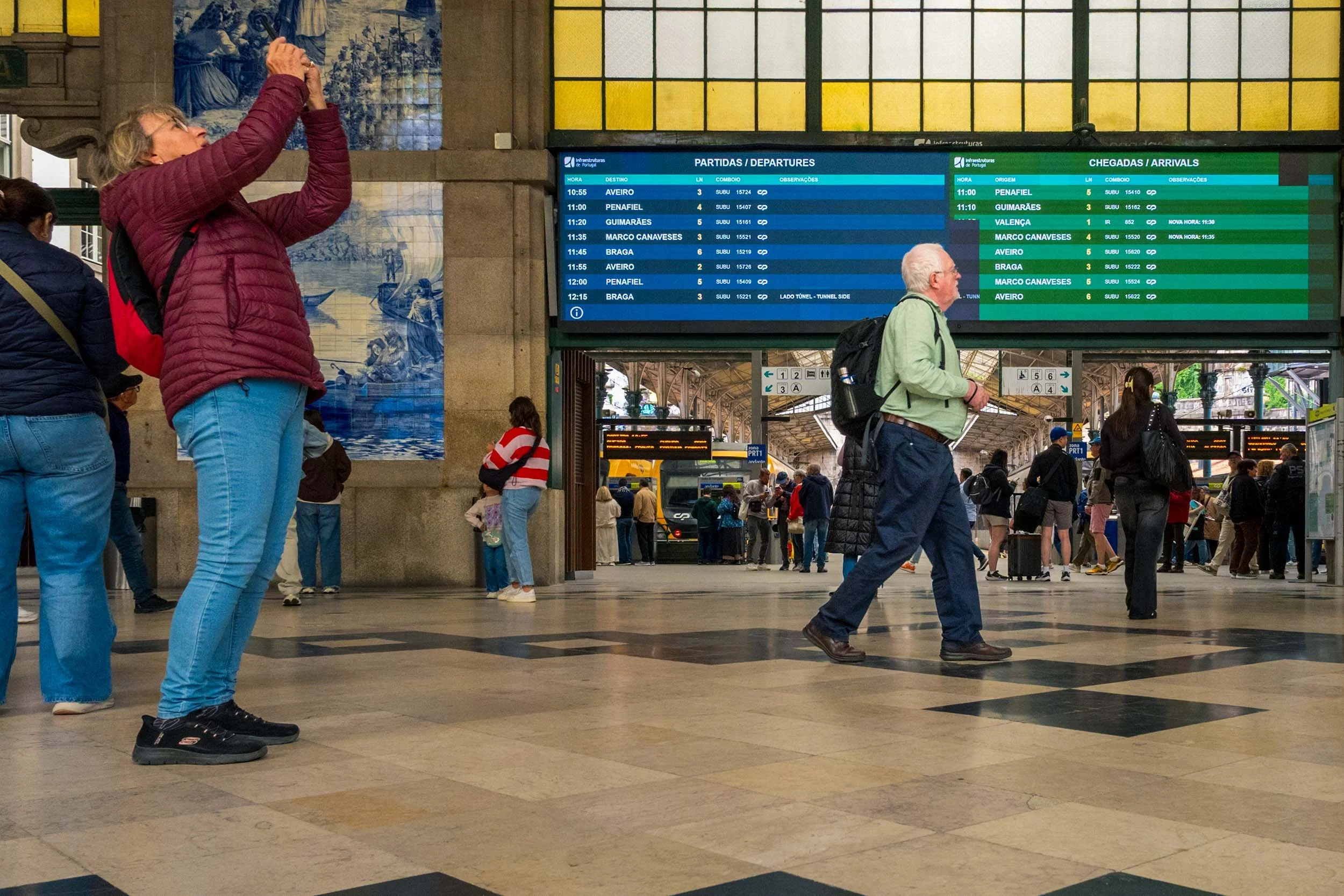 Blue azulejo tiles and passengers inside São Bento train station, Porto