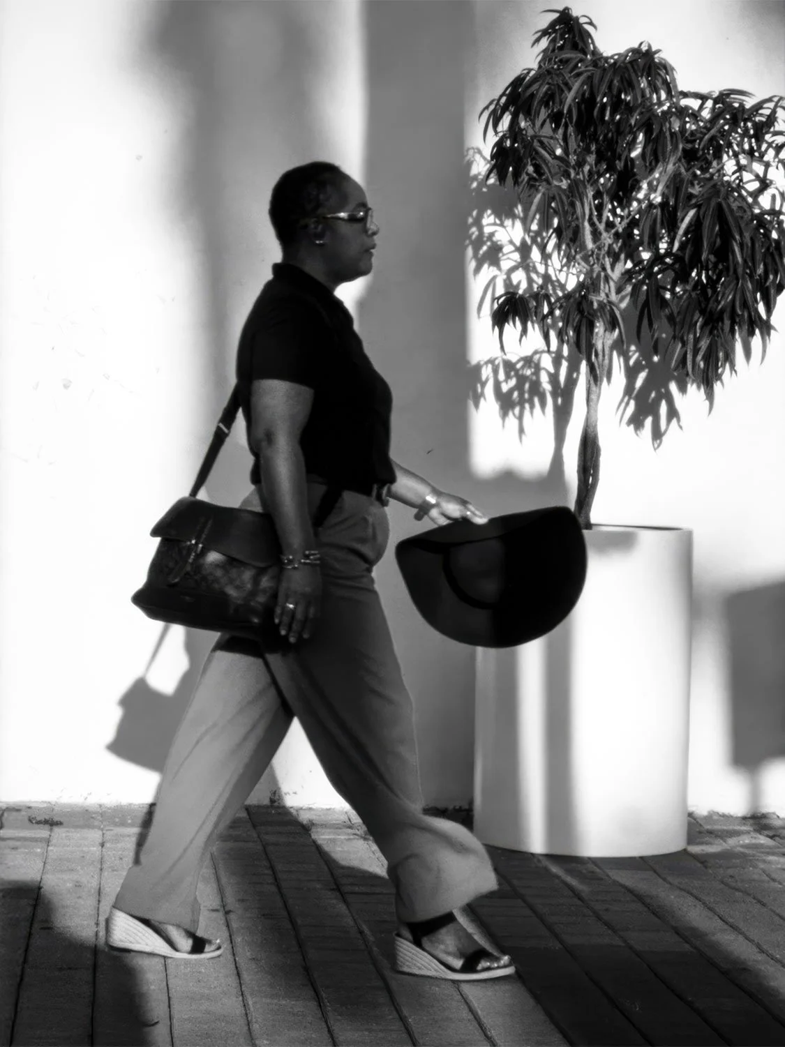 Downtown Miami street style Black woman wide-leg pants black shoulder bag wide-brim hat wedge sandals urban fashion outdoor