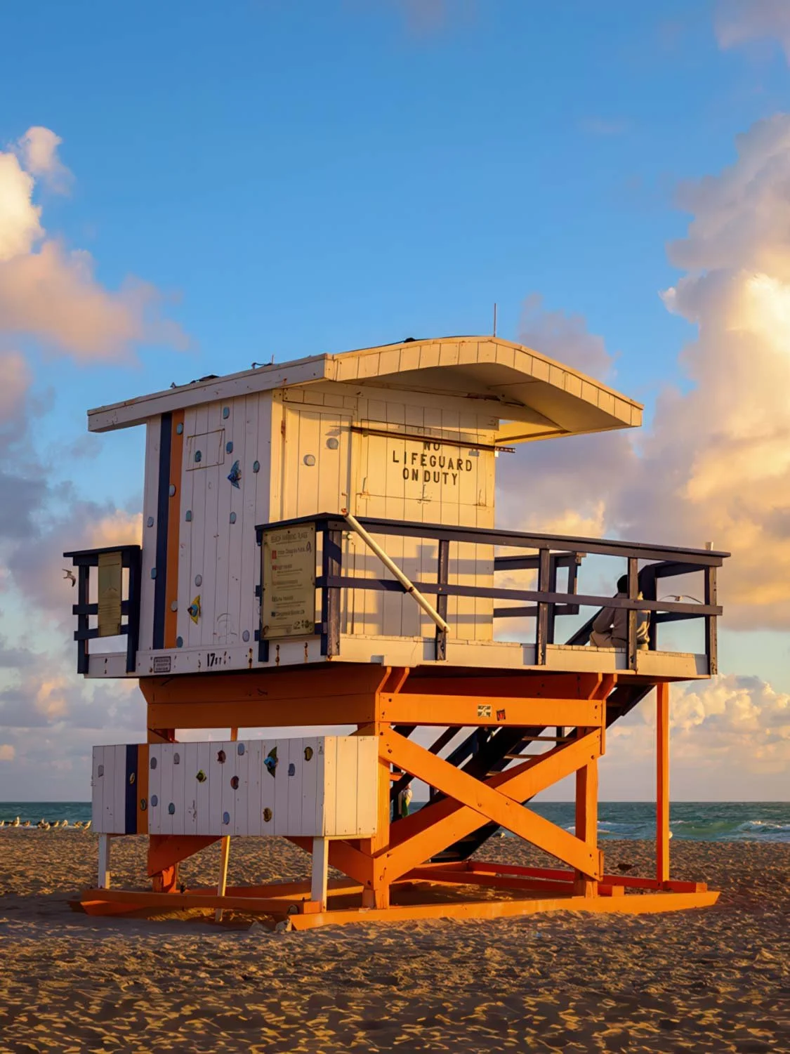 Orange and white Art Deco lifeguard stand on Miami Beach at golden hour with turquoise ocean backdrop