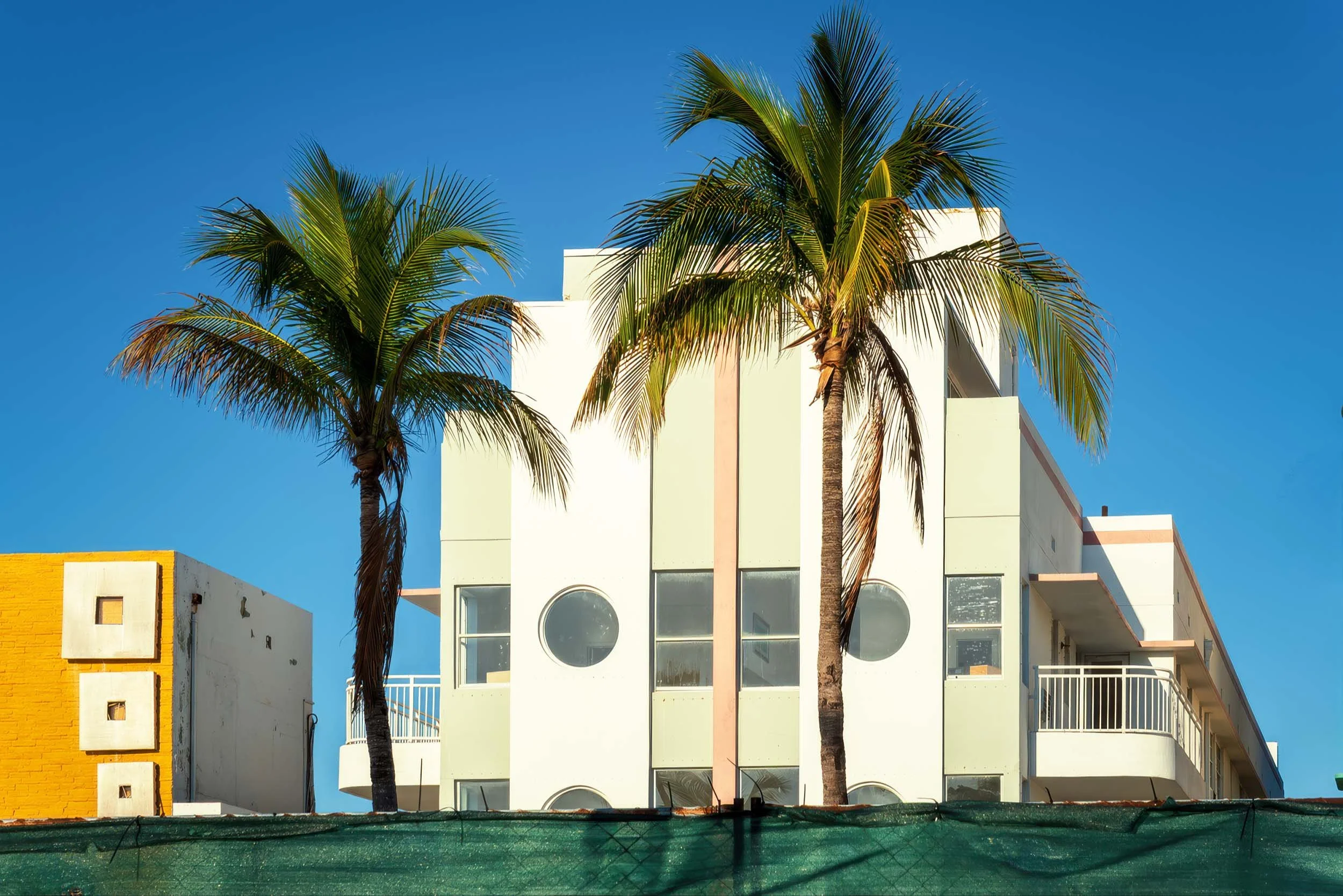 Two MiMo hotel facades on Ocean Terrace framed by palm trees, North Beach Miami