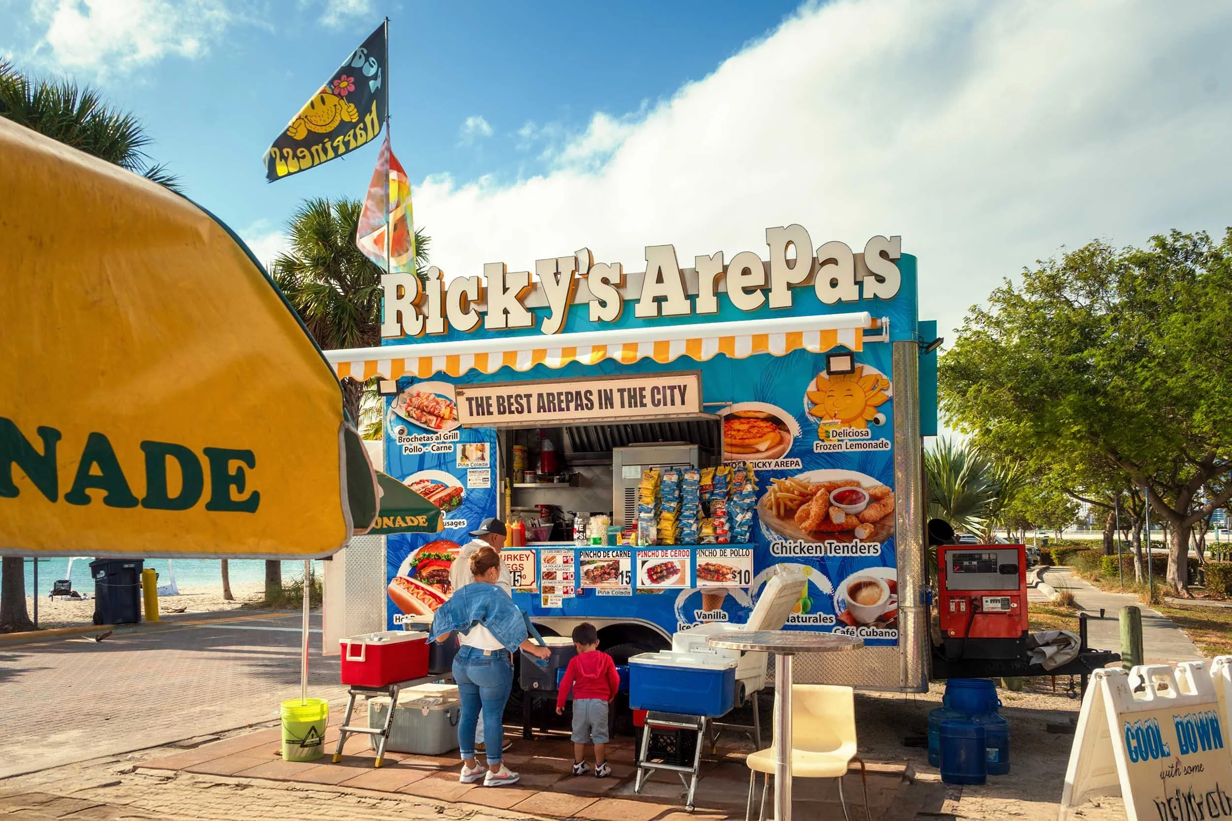 Ricky's Arepas food truck at Hobie Beach Miami with a woman and child ordering at the window