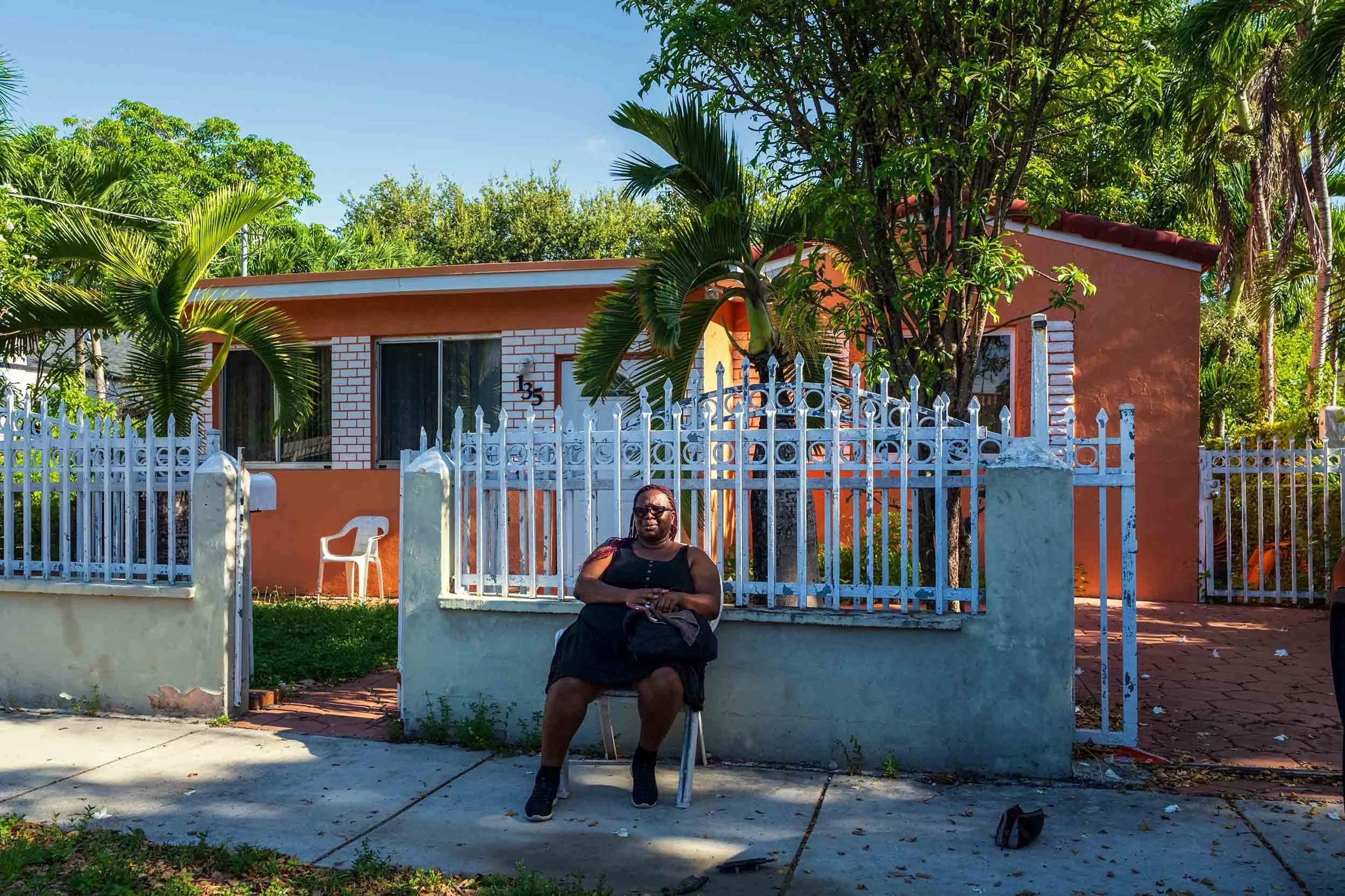 Woman seated outside an orange bungalow, Buena Vista Miami