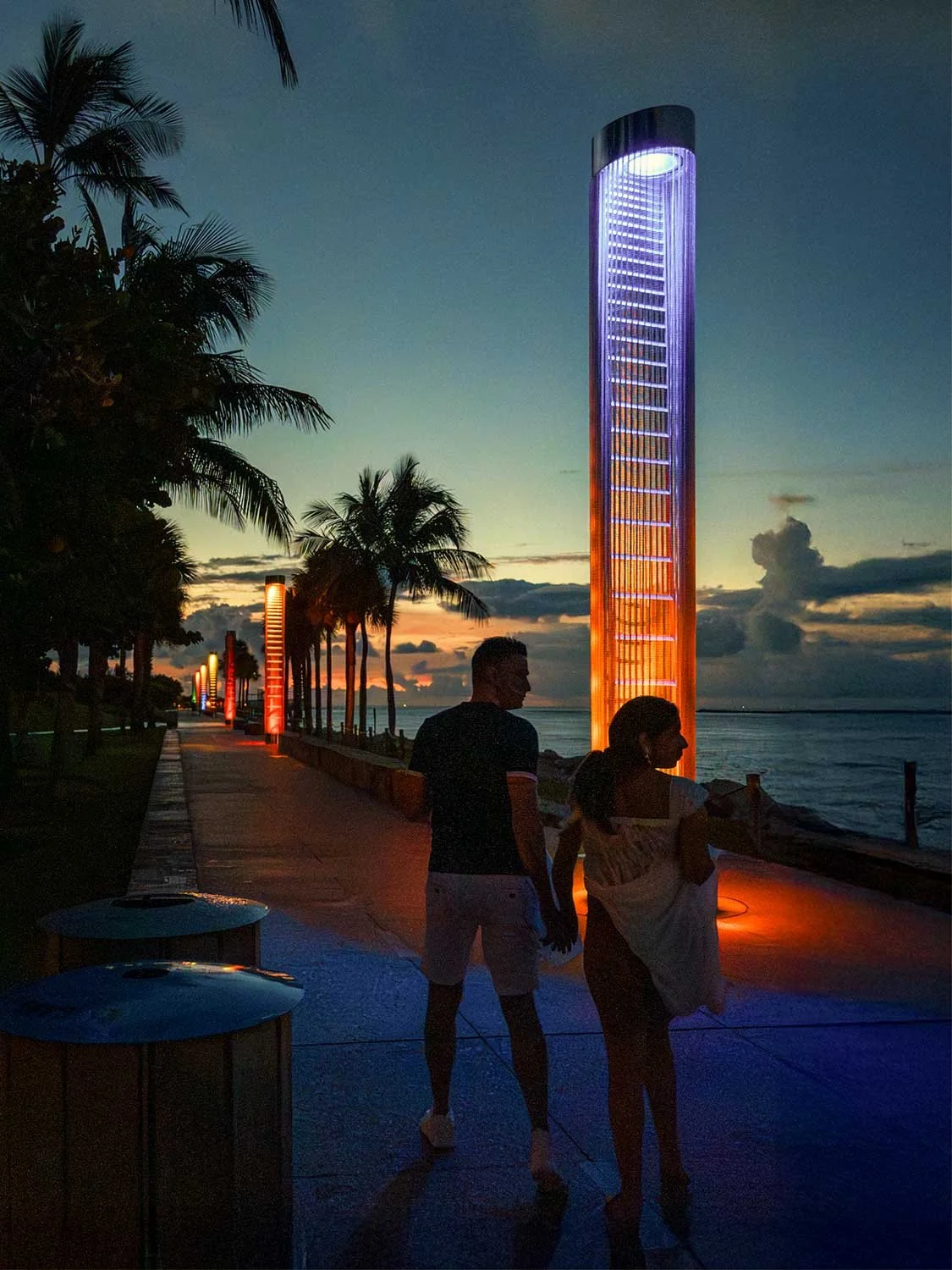 Silhouetted couple walking along the boardwalk in South Pointe Park, South Beach Miami at sunrise, with warm light and ocean views.