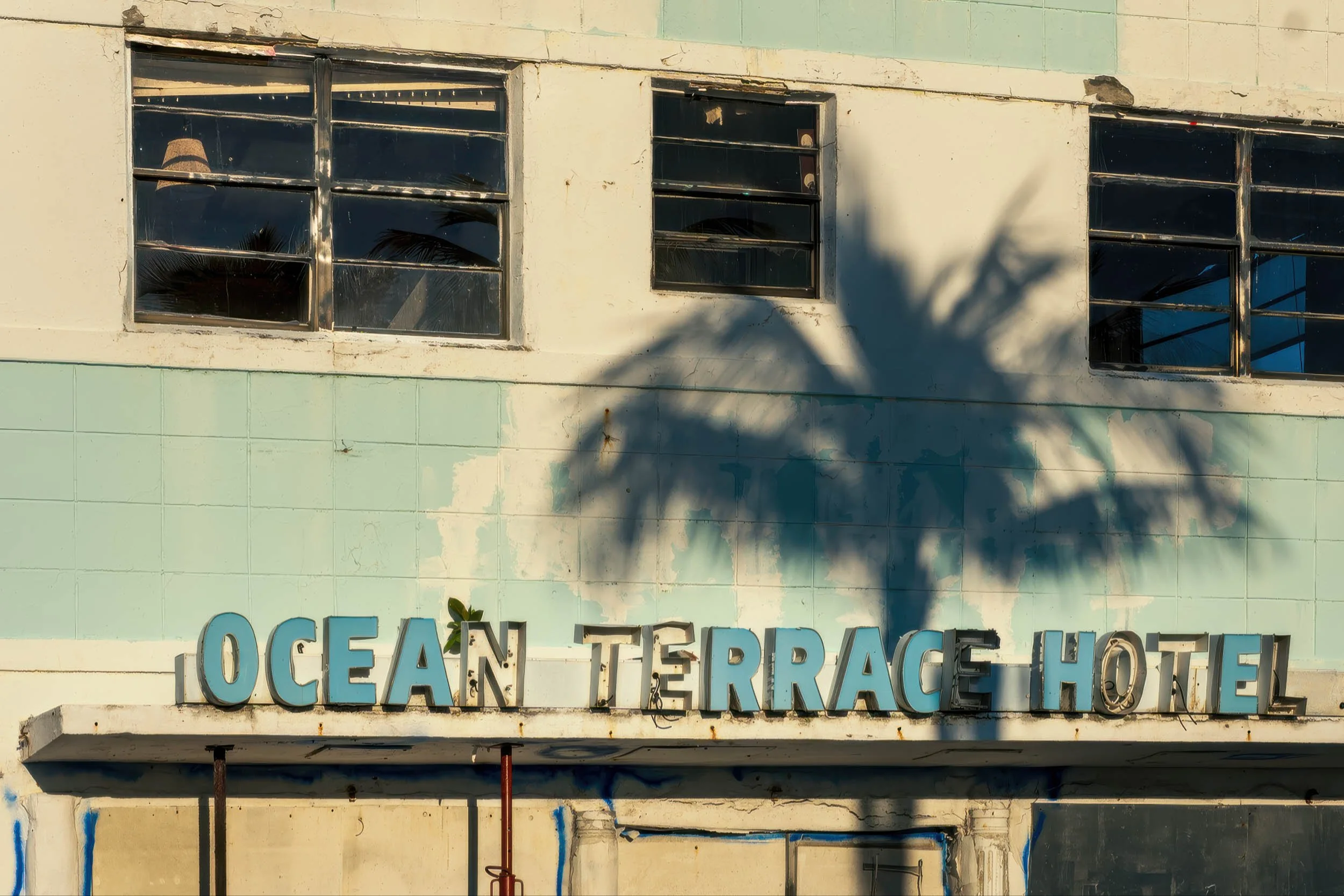 Close-up of vintage OCEAN TERRACE HOTEL channel lettering with palm shadow, North Beach Miami