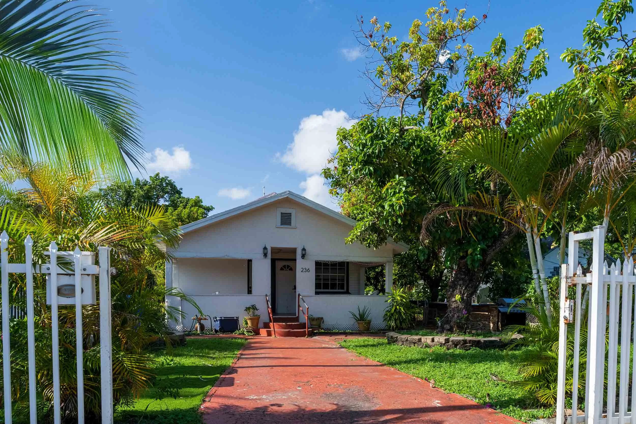 White bungalow with red brick walkway and picket gate, Buena Vista Miami