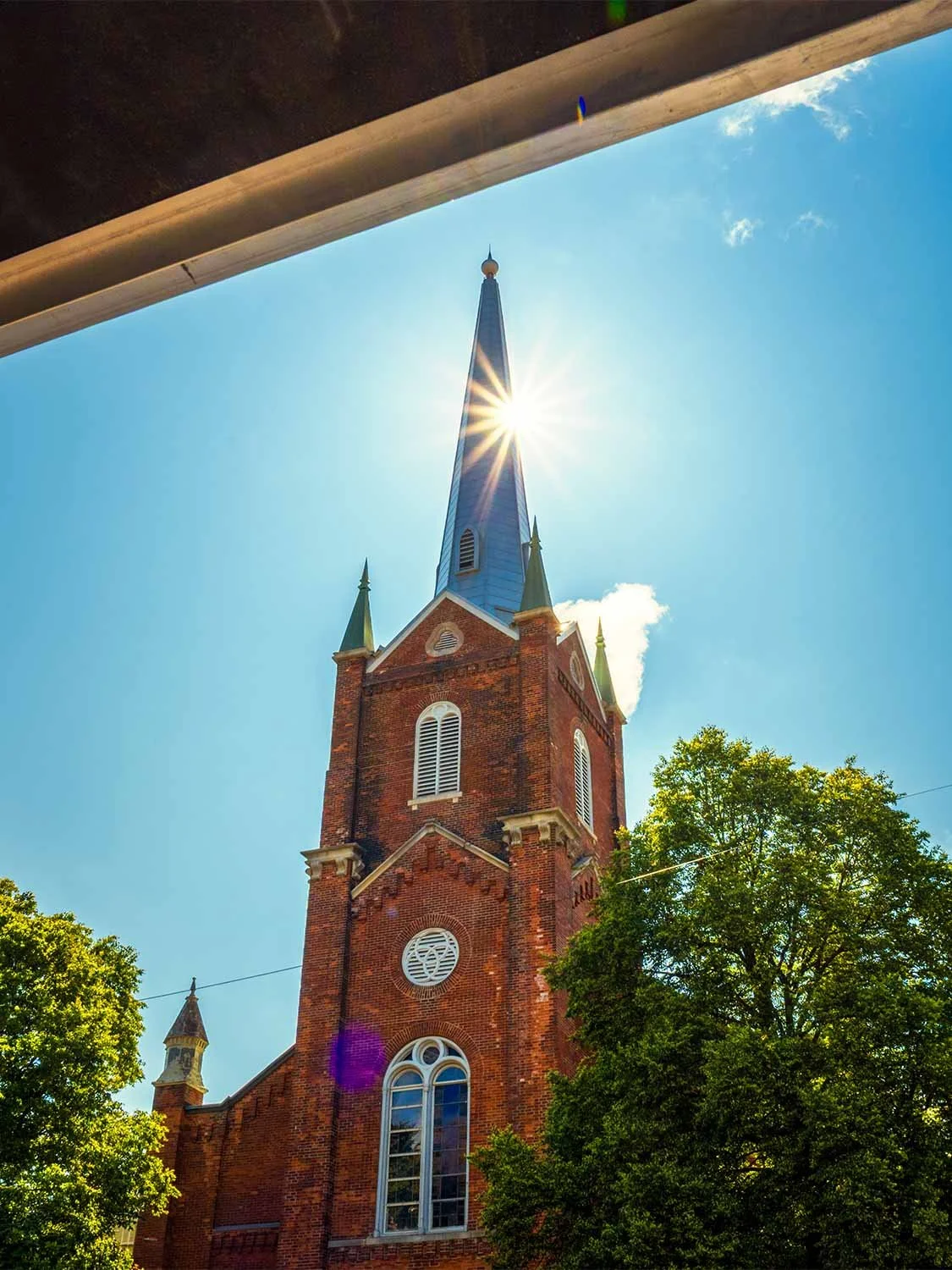 historic brick church steeple sunburst blue sky Gothic architecture landmark religious building exterior