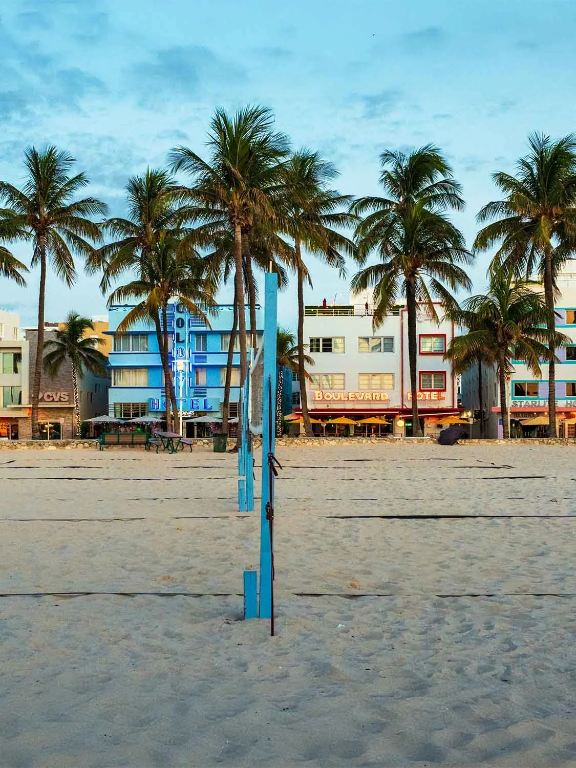 Beach volleyball in Lummus Park, South Beach Miami, with palm trees, sand, and art deco hotels