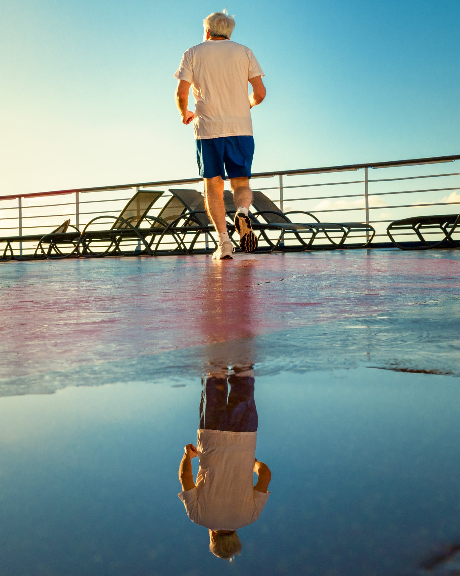 Jogger reflected on wet cruise ship deck at sunrise
