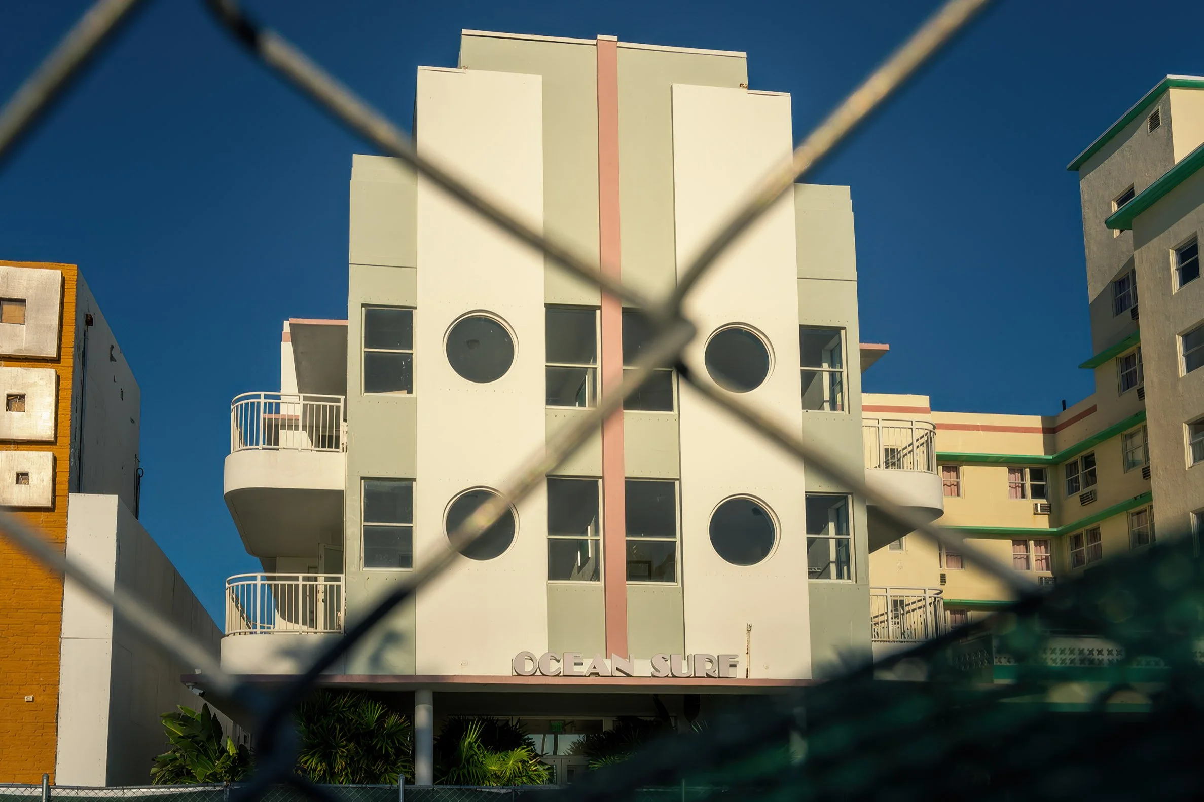 Ocean Surf Hotel facade shot through construction chain-link fence, North Beach Miami