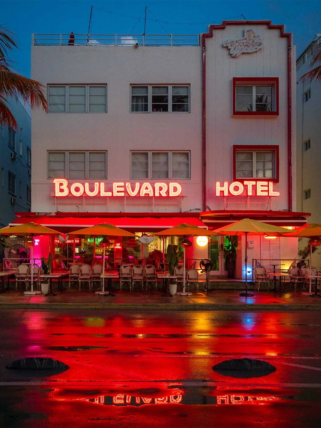 Boulevard Hotel Miami Beach neon sign Art Deco building Ocean Drive outdoor dining rainy night