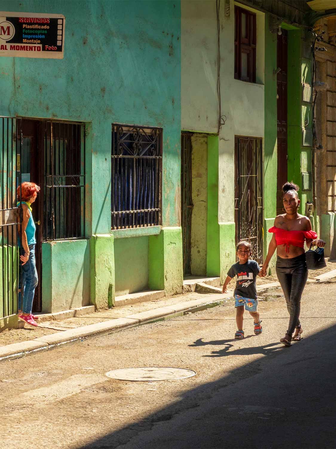 Latin America street photography, colorful colonial architecture, mother and child walking, vibrant urban life Cuba.