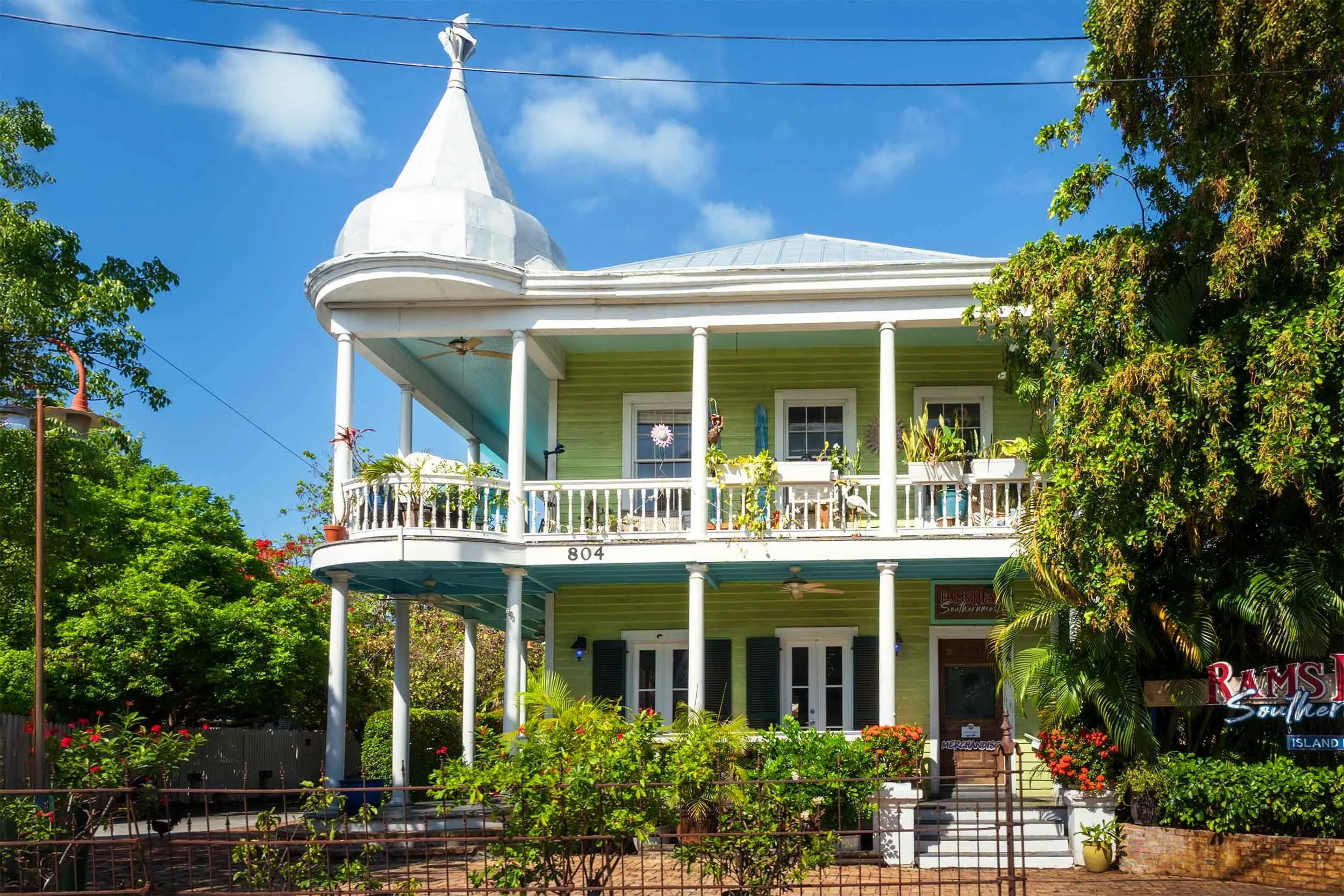 Two-story green Victorian building with white columns, wraparound balcony, and turret at 804 in Key West, FL
