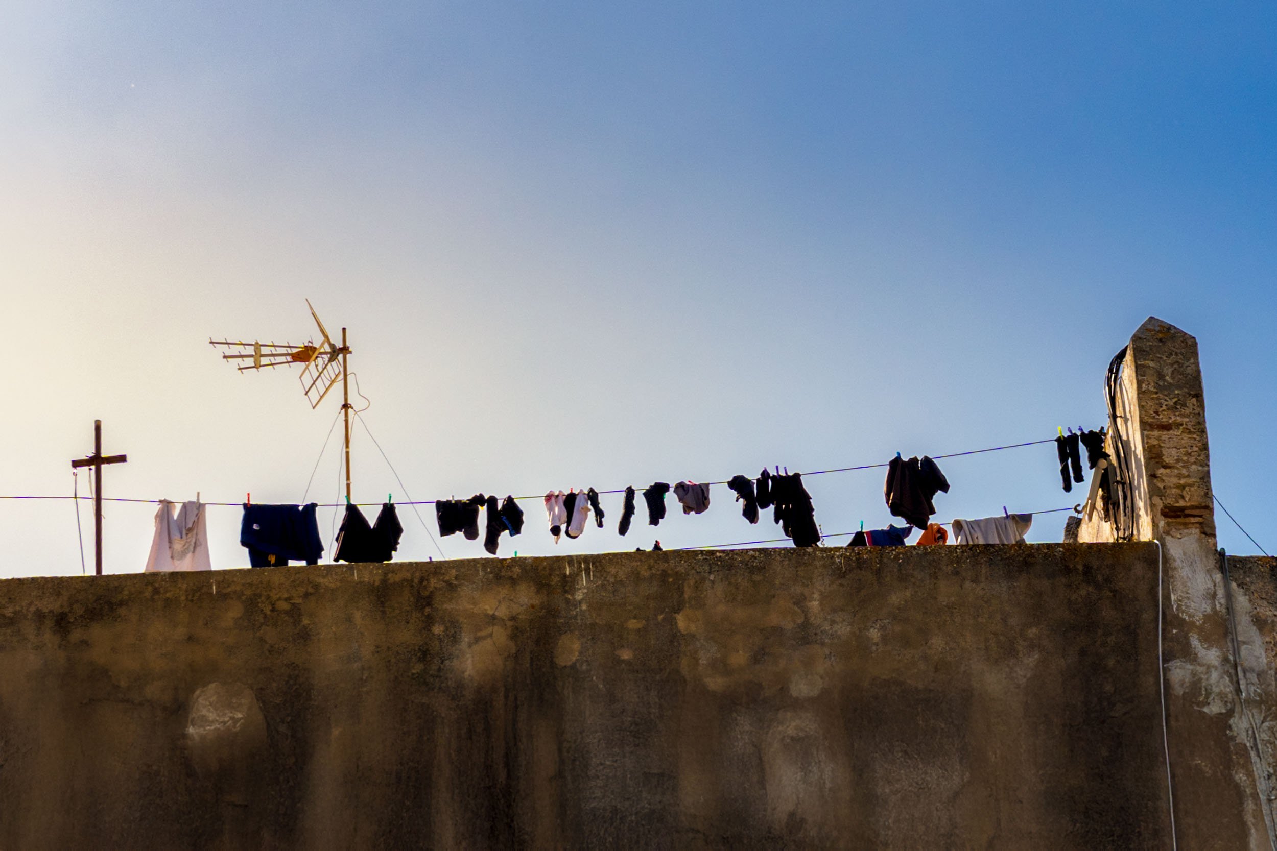 Cadiz Spain street photography clothesline laundry drying rooftop stone wall antenna sunny day travel