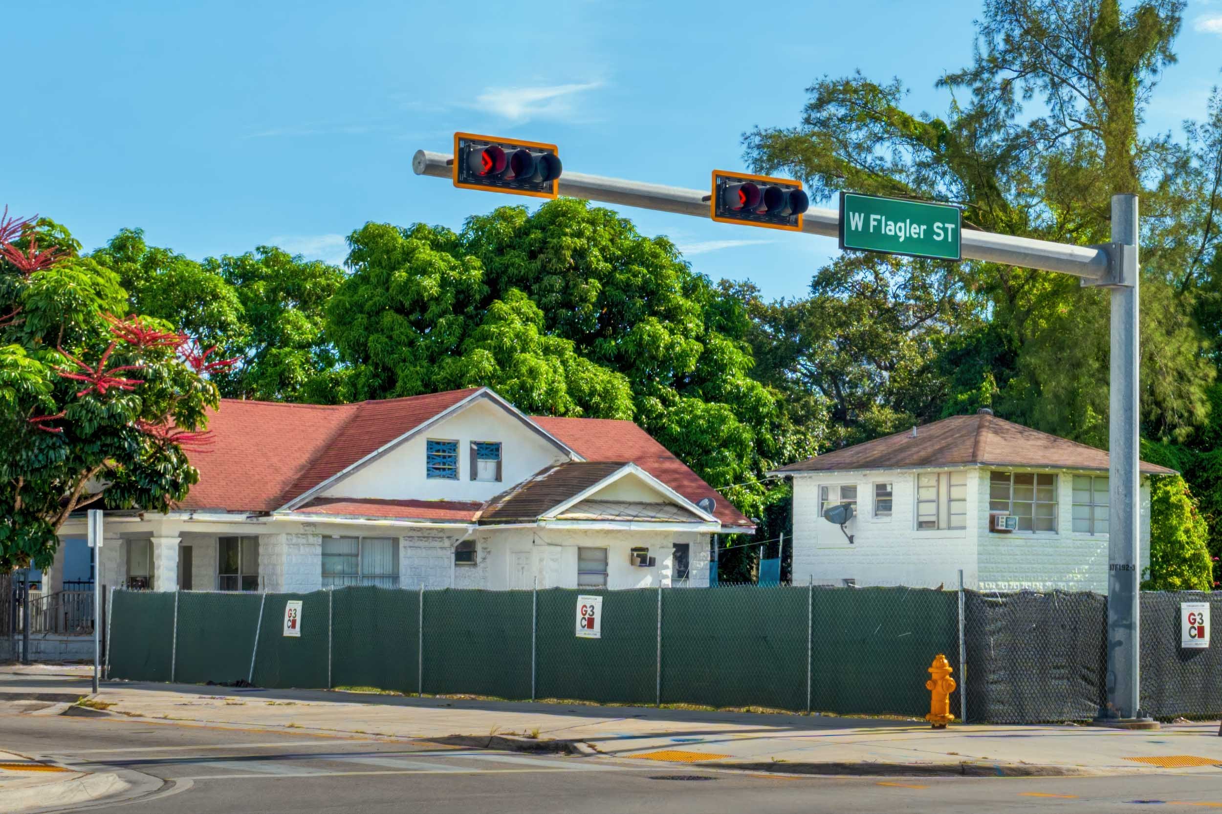 Wood-frame houses behind demolition fencing on West Flagler Street, Miami