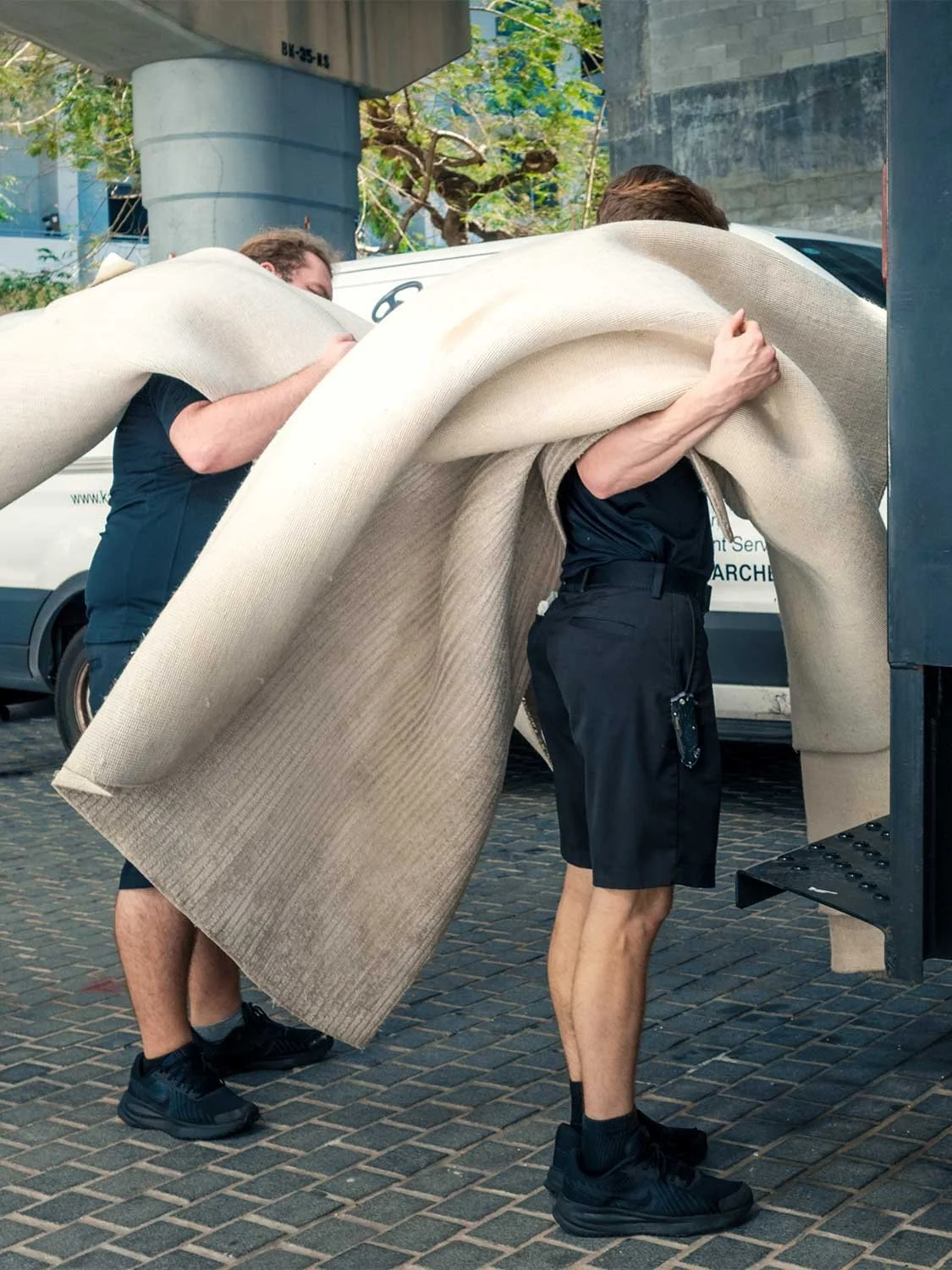 rug delivery Brickell Miami two movers unloading large area rug from truck professional flooring service