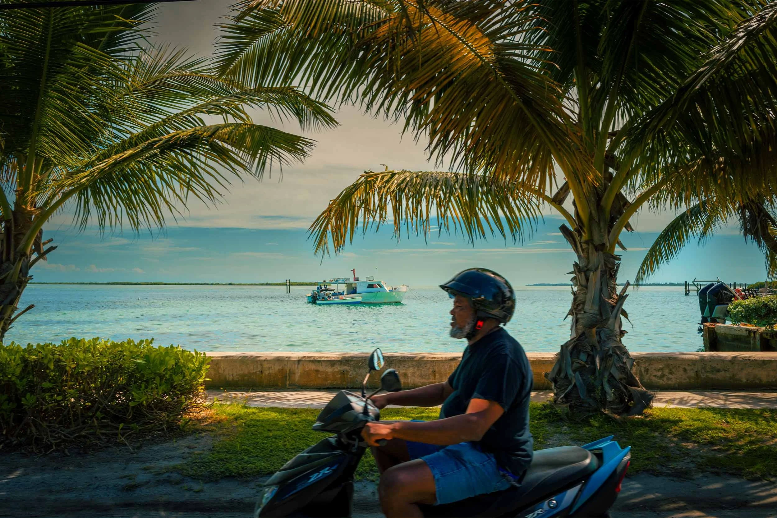 Rider on scooter passes a boat in the water in Bimini Bahamas - Miami Photographer