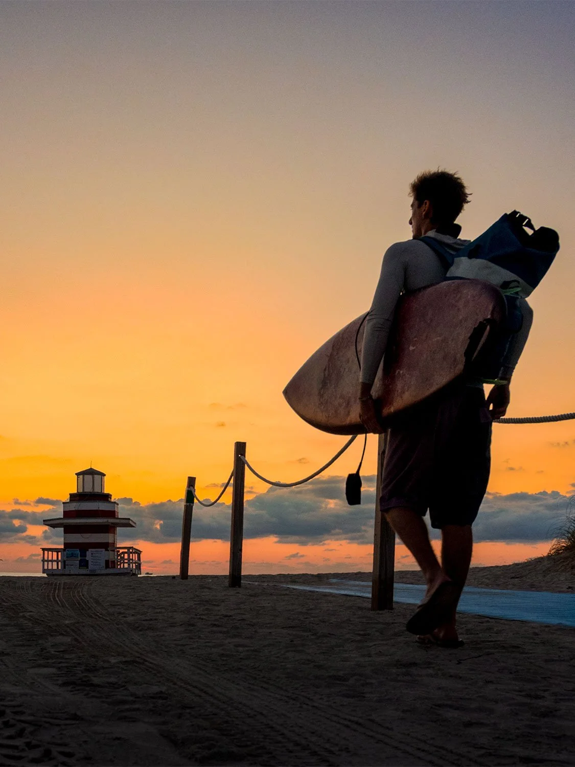 South Beach sunrise surfer with surfboard and leash on sandy beach Miami golden hour coastal lifestyle photography