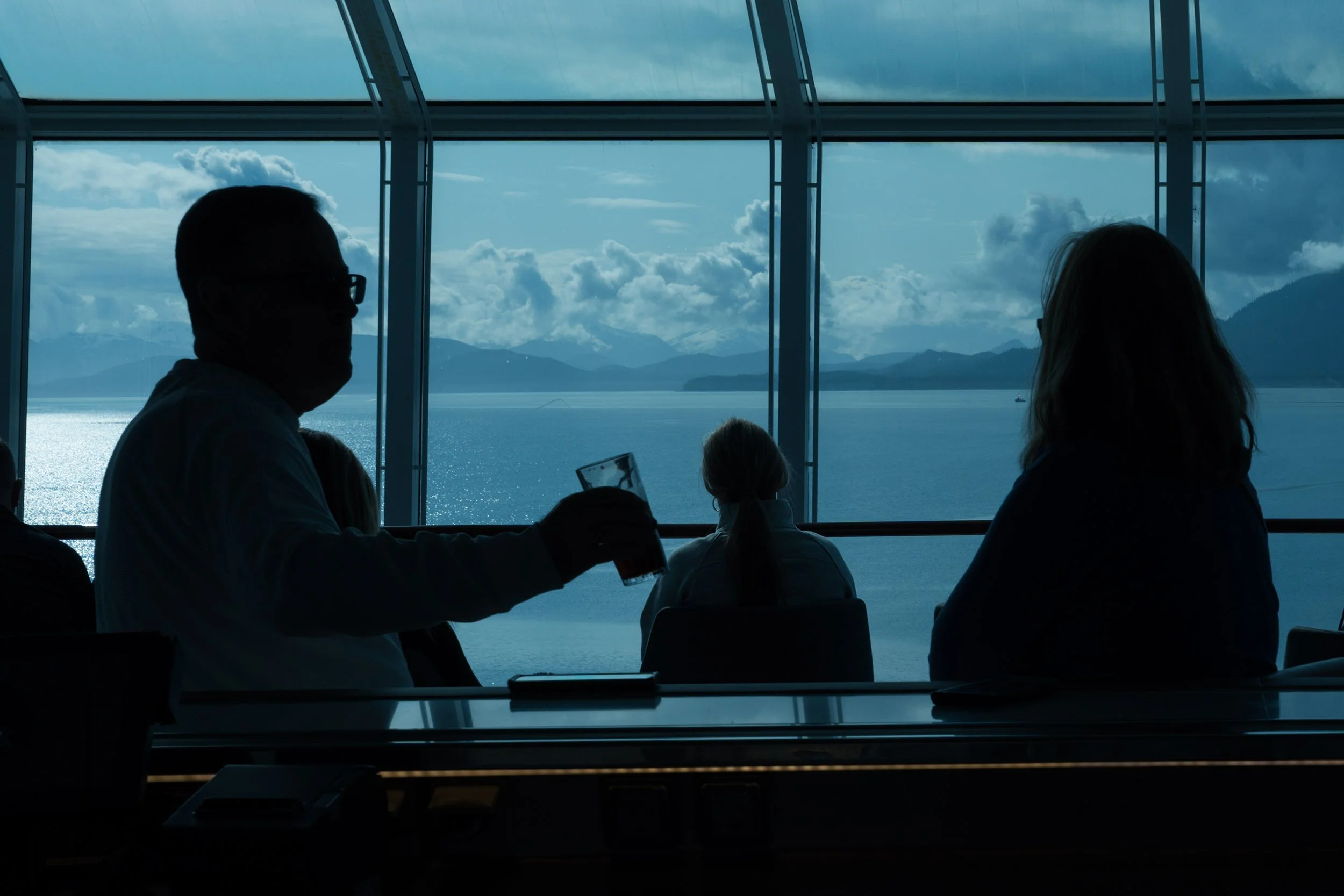 Silhouetted bartender pouring a drink against ship window at sunset