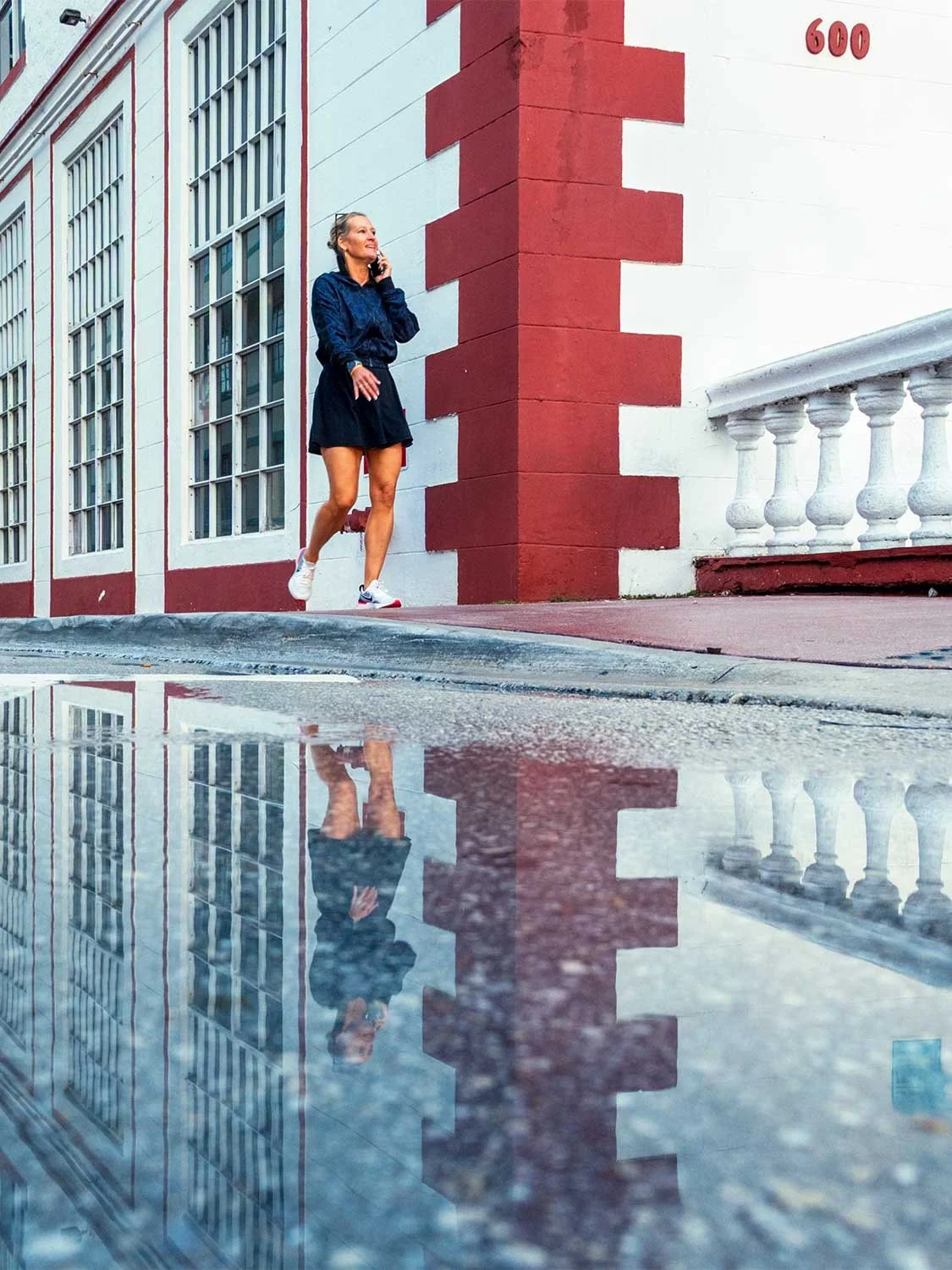 South Beach street style woman walking outdoors urban architecture puddle reflection Nike sneakers Miami