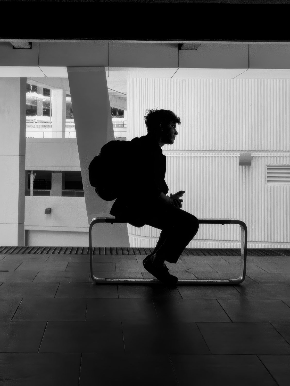 Man on bench silhouette Black and white silhouette of a man sitting on a bench with a backpack at a Miami transit station