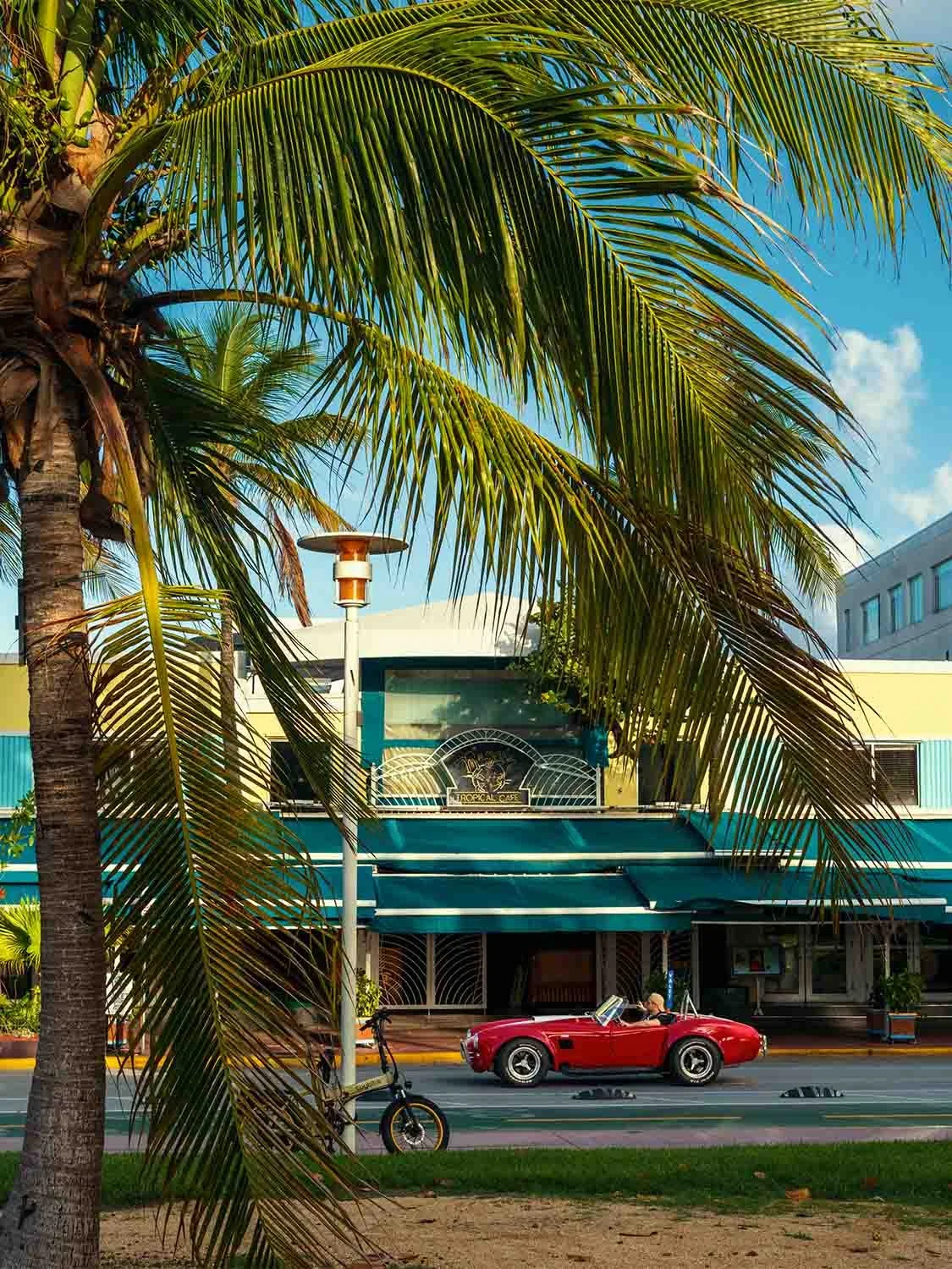 Miami Beach Art Deco district red vintage Shelby Cobra convertible Ocean Drive Tropical Cafe palm trees sunny day