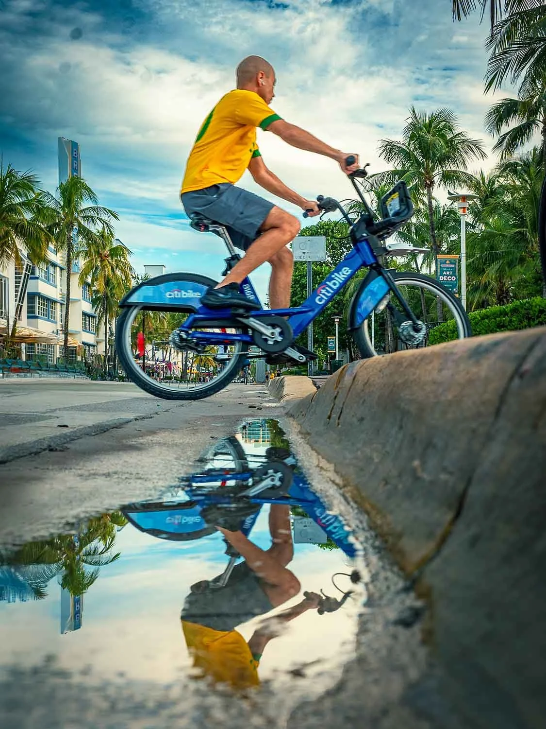 Bike rider creates a water reflection going over the curb on Ocean Drive in South Beach Miami