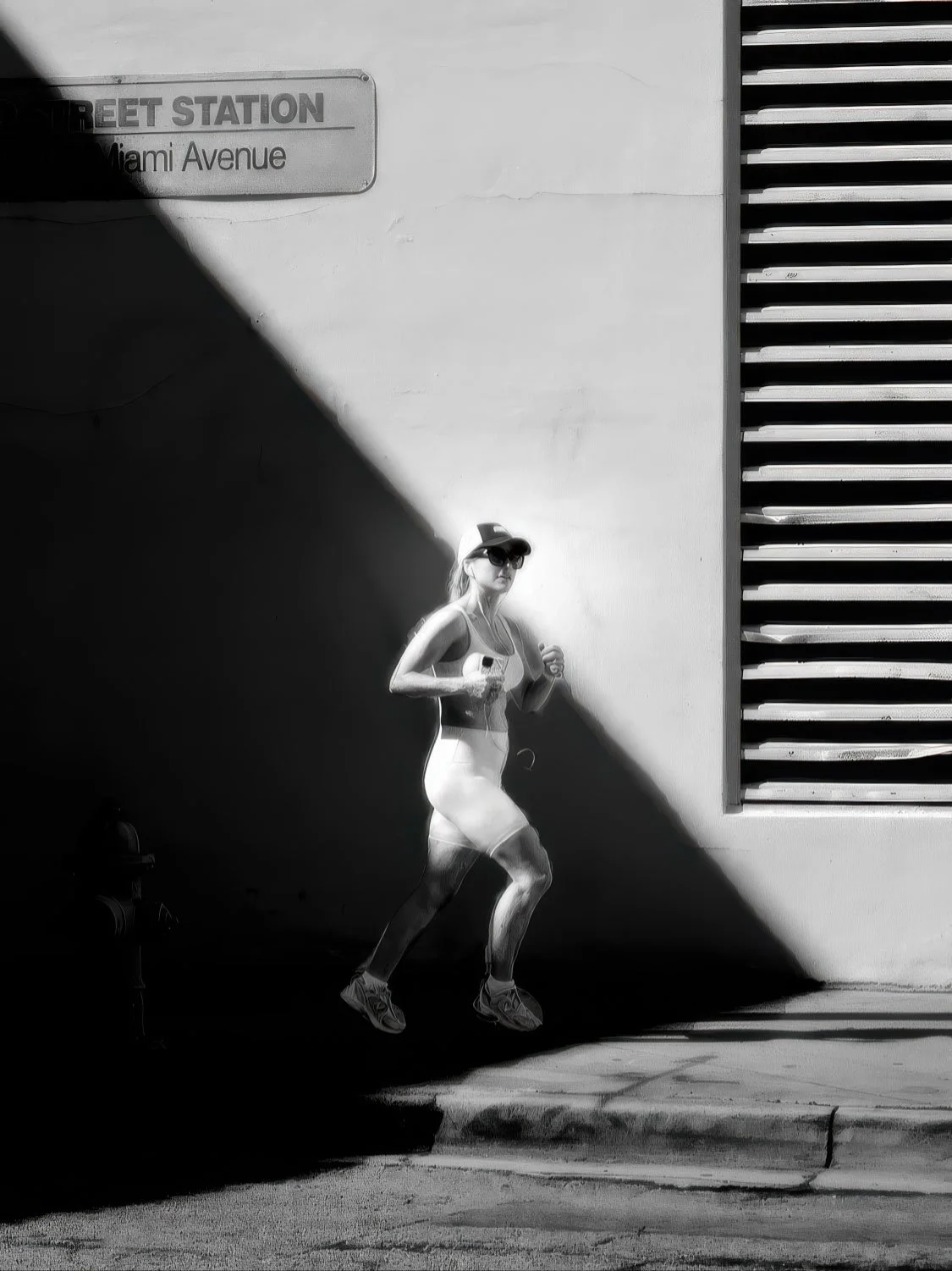 Woman running at Miami Avenue Station Black and white photo of a woman running through a dramatic shaft of light and shadow near Miami Avenue Station