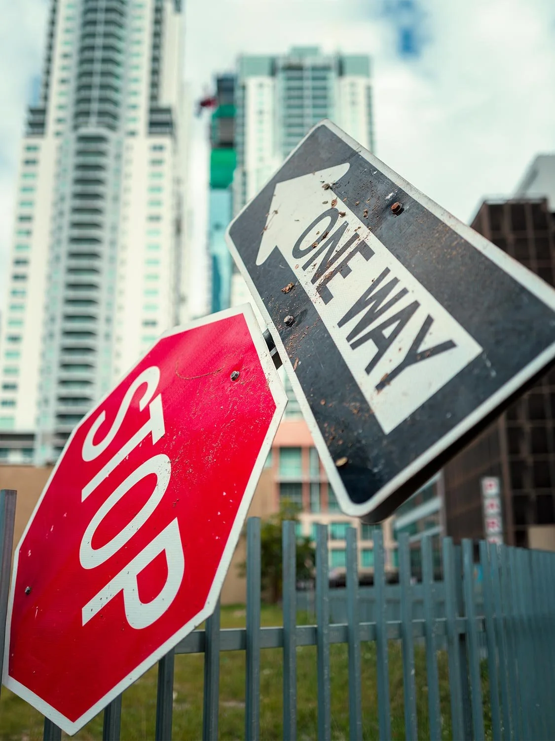 urban street signs stop sign one way sign city background skyscrapers fence outdoor photography