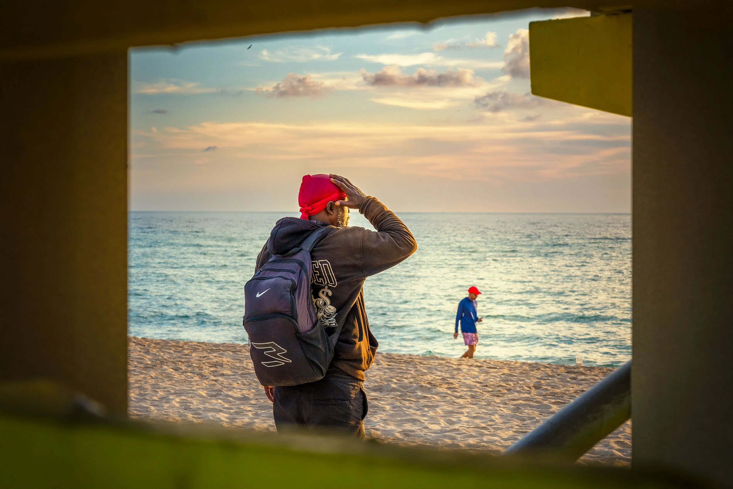 

The sunshine forces a tourist to shield his eyes at sunrise on South Beach in Miami Beach