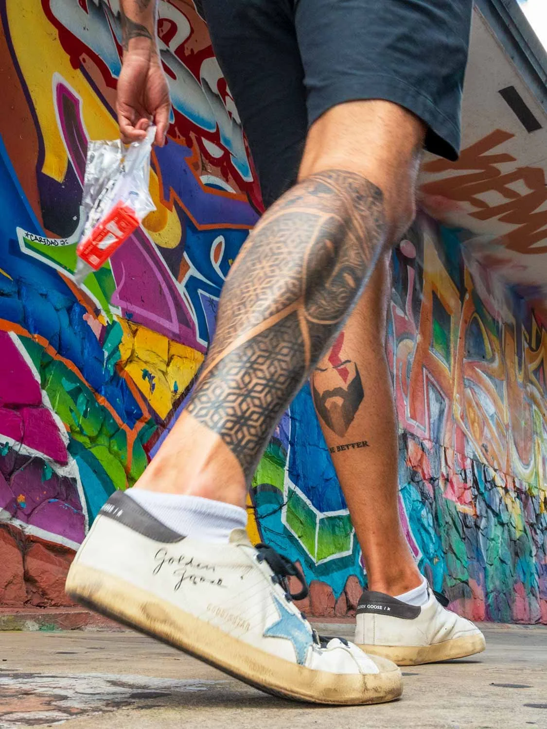 Tattooed legs and Golden Goose sneakers mid-stride in front of a colorful graffiti wall in Wynwood Miami  Each one leads with the subject, includes location where it strengthens SEO, and avoids anything that reads like marketing copy. Let me know if 