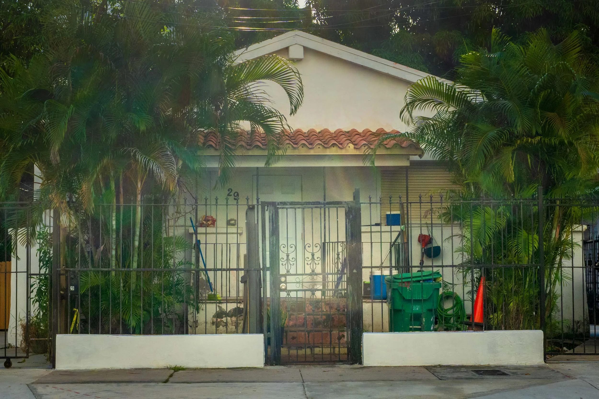Spanish tile-roof cottage with an iron gate and palm trees, Miami
