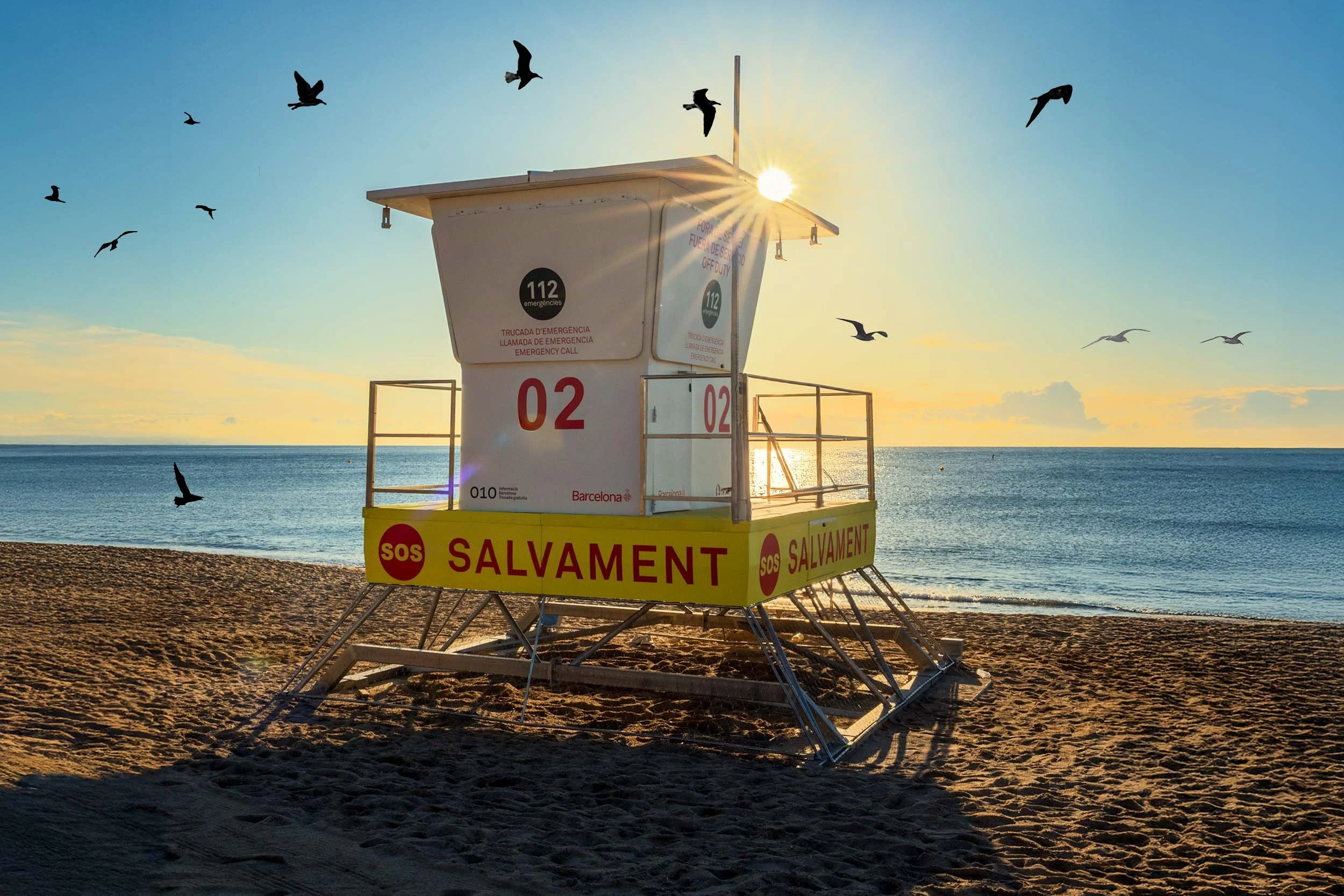 Yellow and white Salvament lifeguard tower number 02 on the sand at sunrise, seagulls flying overhead